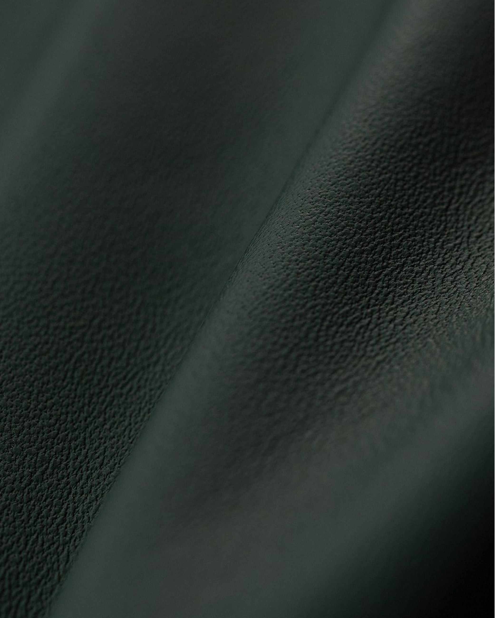 Close-up of dark green textured fabric with a visible seam running diagonally.