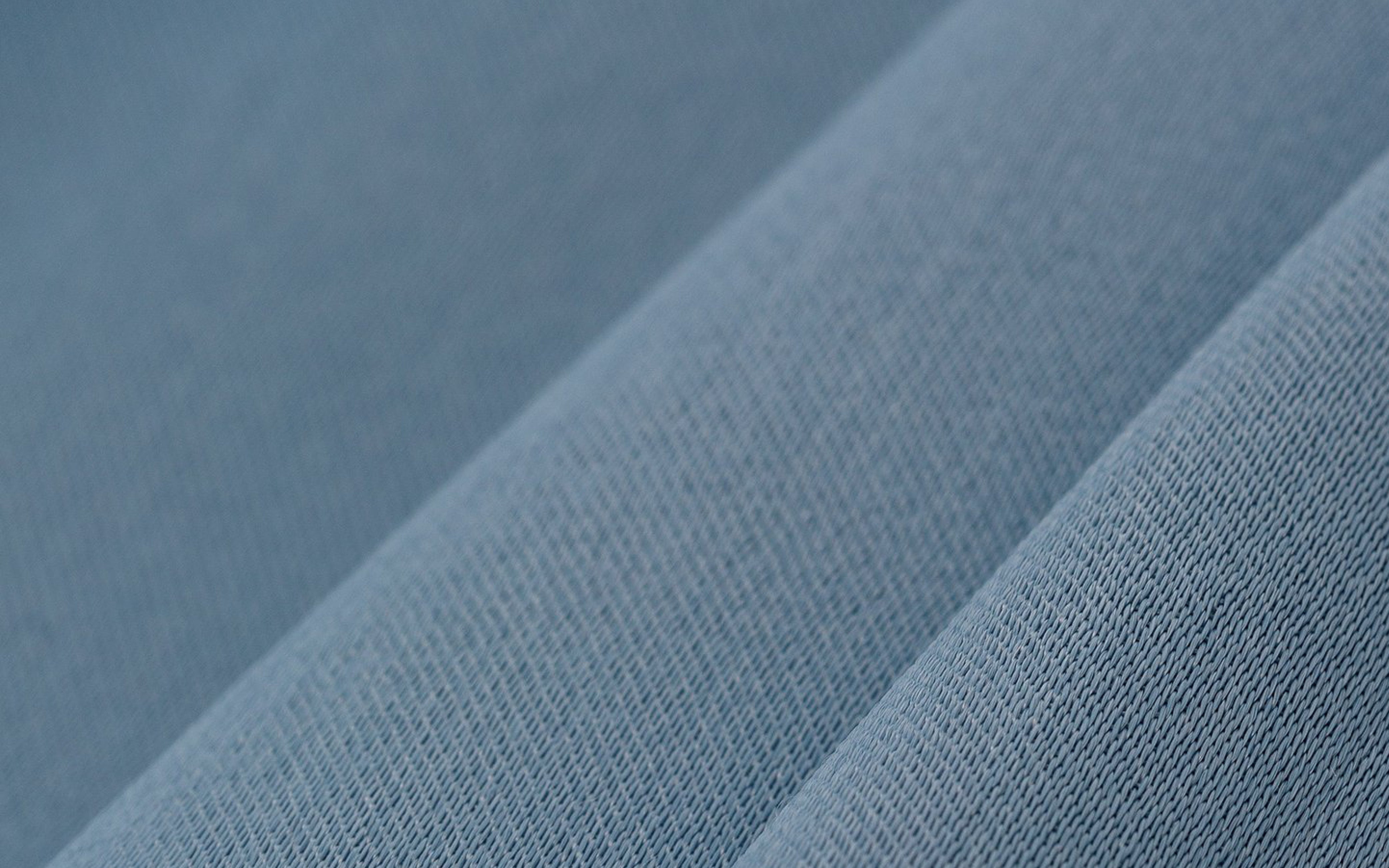 Close-up of blue textured fabric with diagonal folds creating parallel lines.