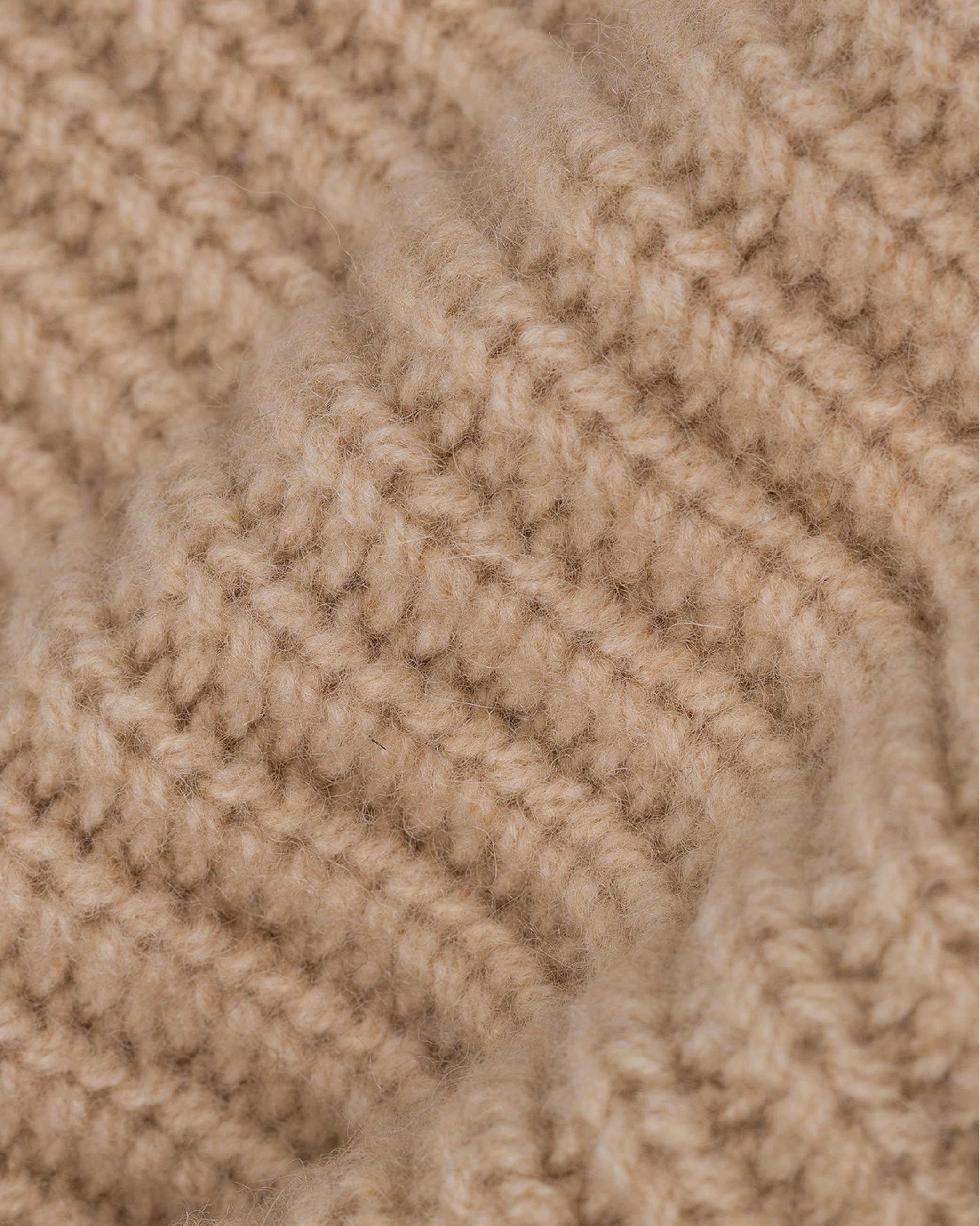 Close-up of textured, ribbed, light brown knitted fabric with soft, fuzzy fibers.