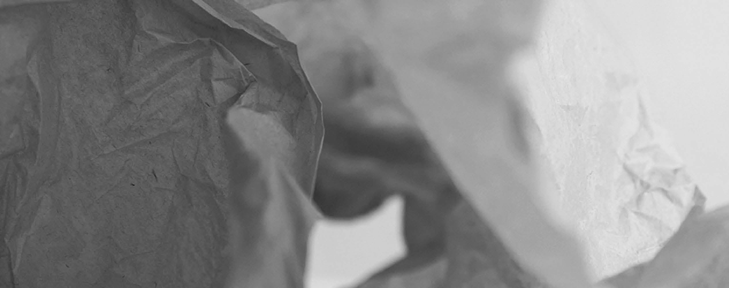 Close-up of crumpled tissue paper in grayscale, showing texture and folds with soft lighting.