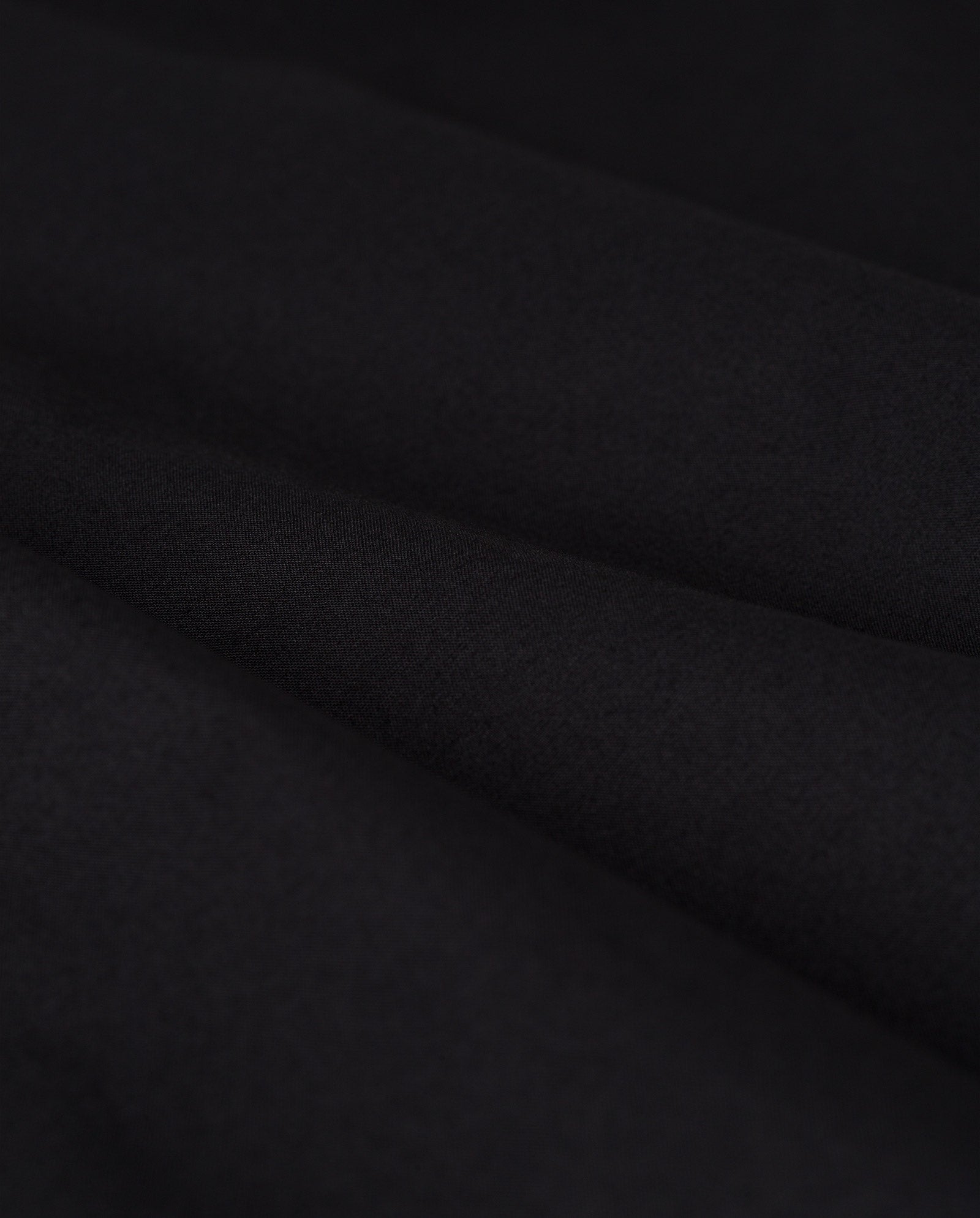 Close-up of the black SIENNA Skirt by IVY OAK, showcasing its smooth, matte texture and soft folds that highlight the skirt’s elegant and voluminous drape.