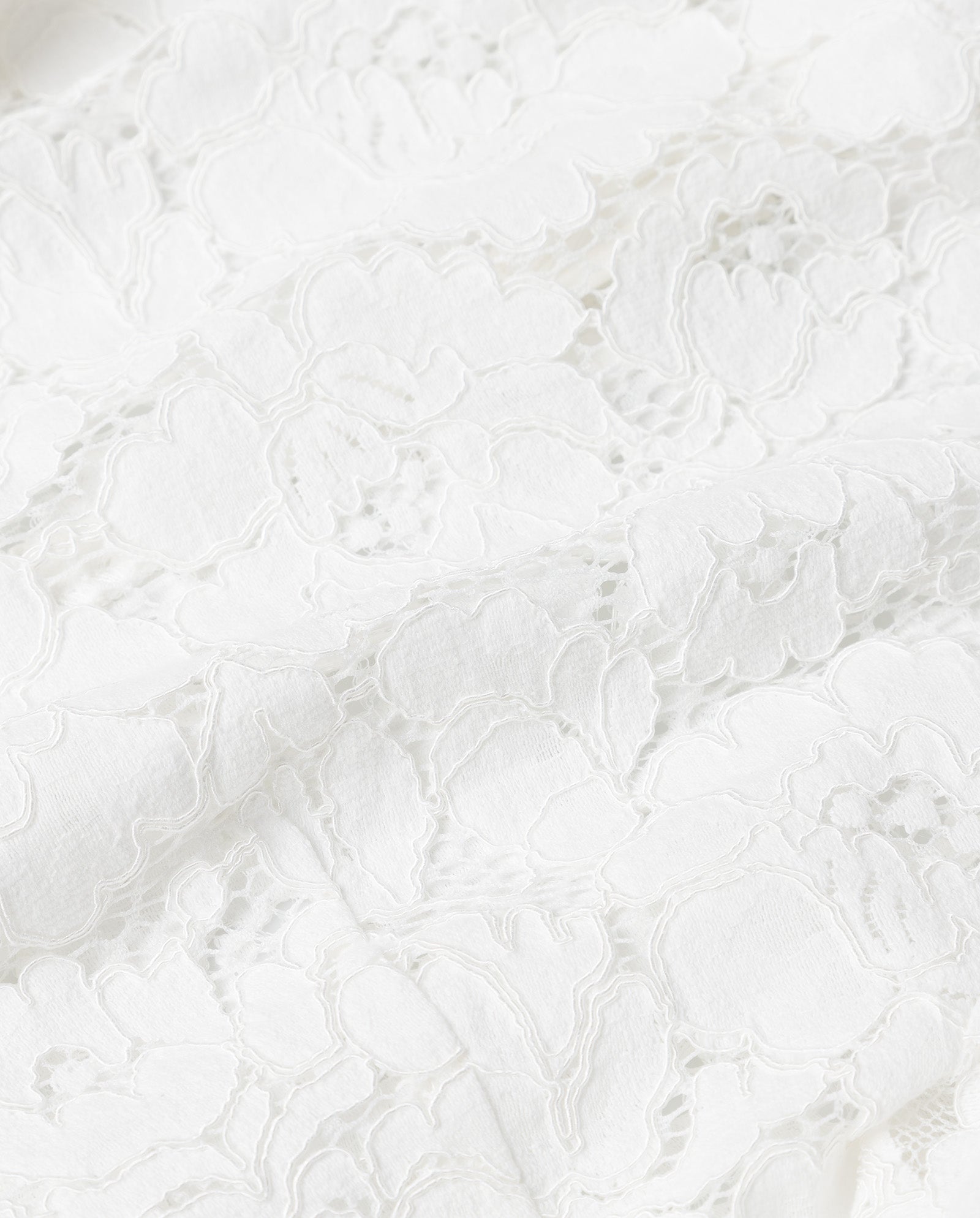 Close-up of the TRACEY Top by IVY OAK, featuring white floral lace fabric with intricate, delicate patterns and a slightly textured surface, crafted from fine viscose.