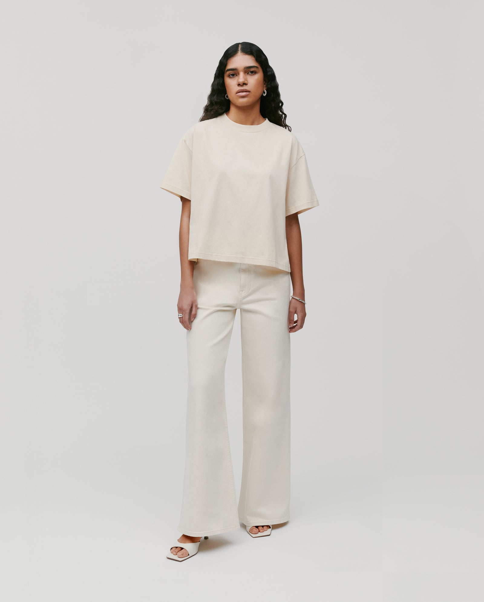 Woman wearing the KYLA Top by IVY OAK—a must-have boxy organic cotton T-shirt—paired with wide-leg pants, standing against a plain white background.