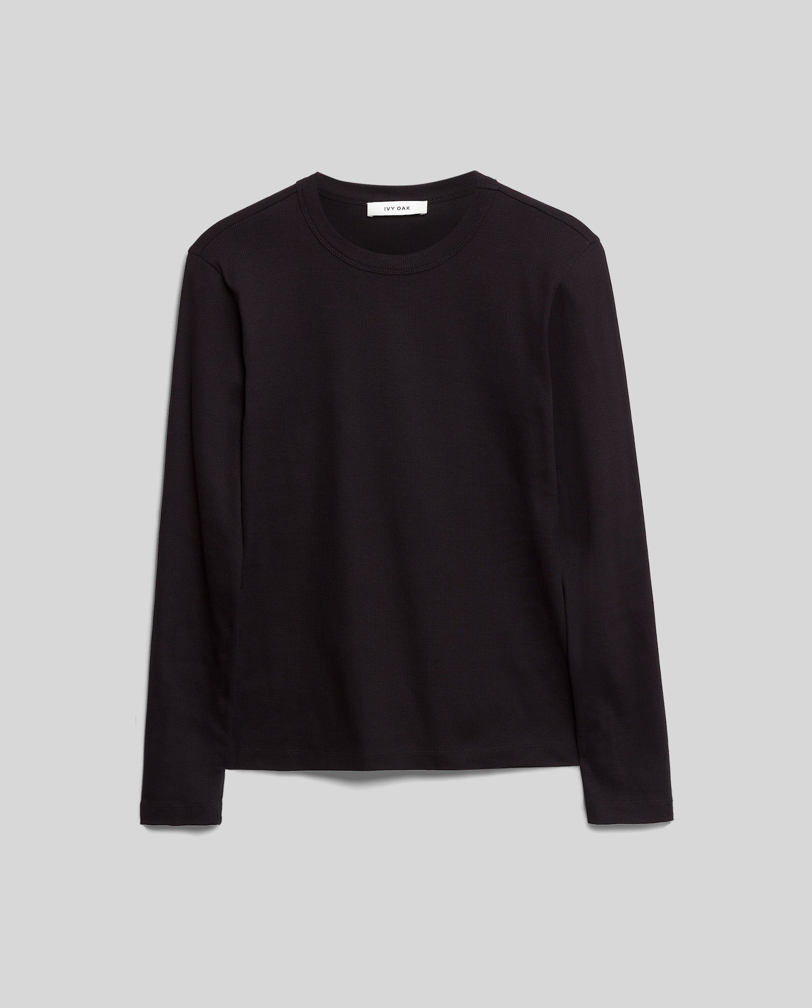 The IVY OAK KOLLINA Top is a comfortable, plain black long-sleeve crewneck, crafted from organic cotton and shown against a light gray background.