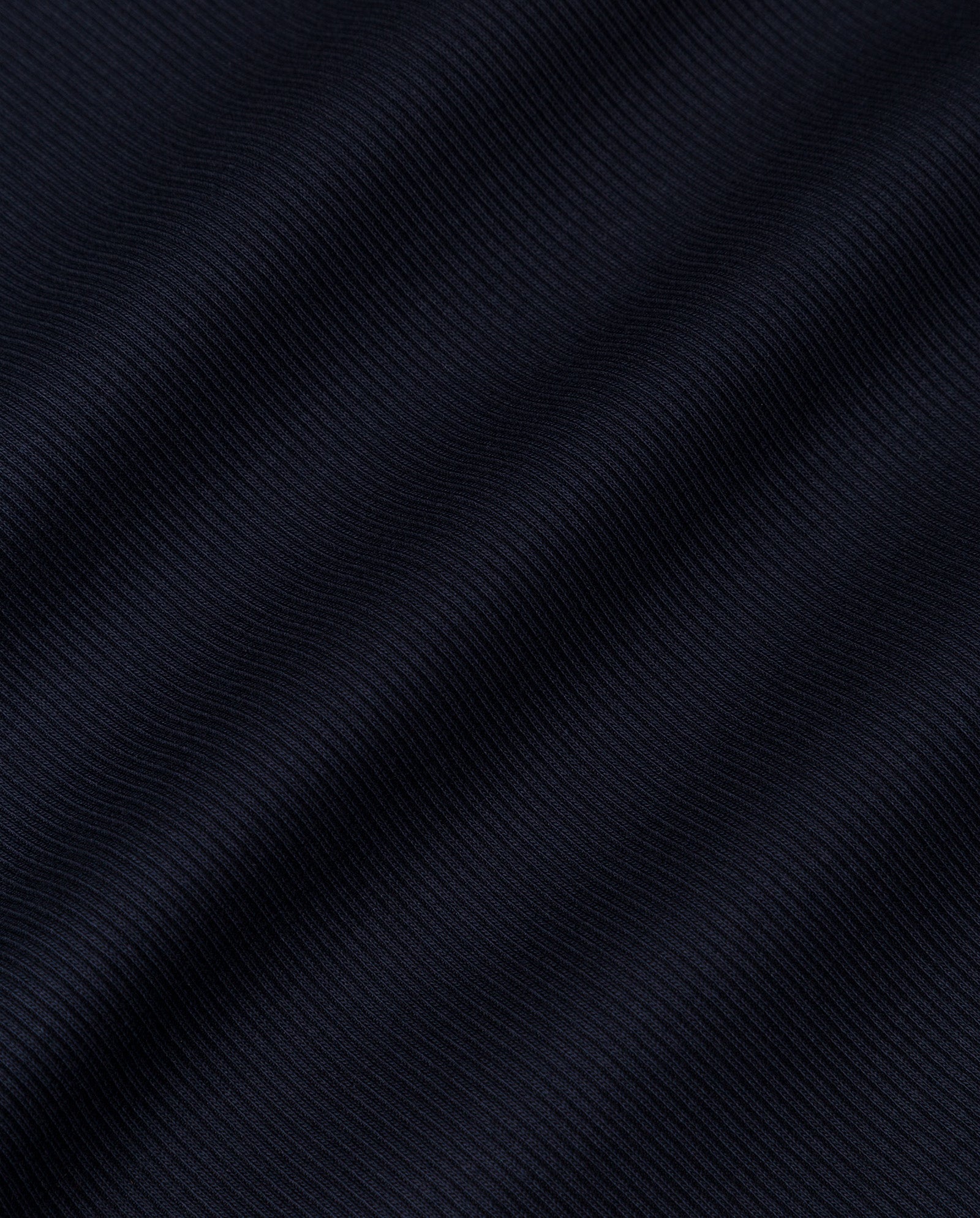 Close-up of the KOLLINA Top by IVY OAK, crafted from dark ribbed organic cotton fabric with horizontal textured lines and gentle waves, perfect for comfortable wear.