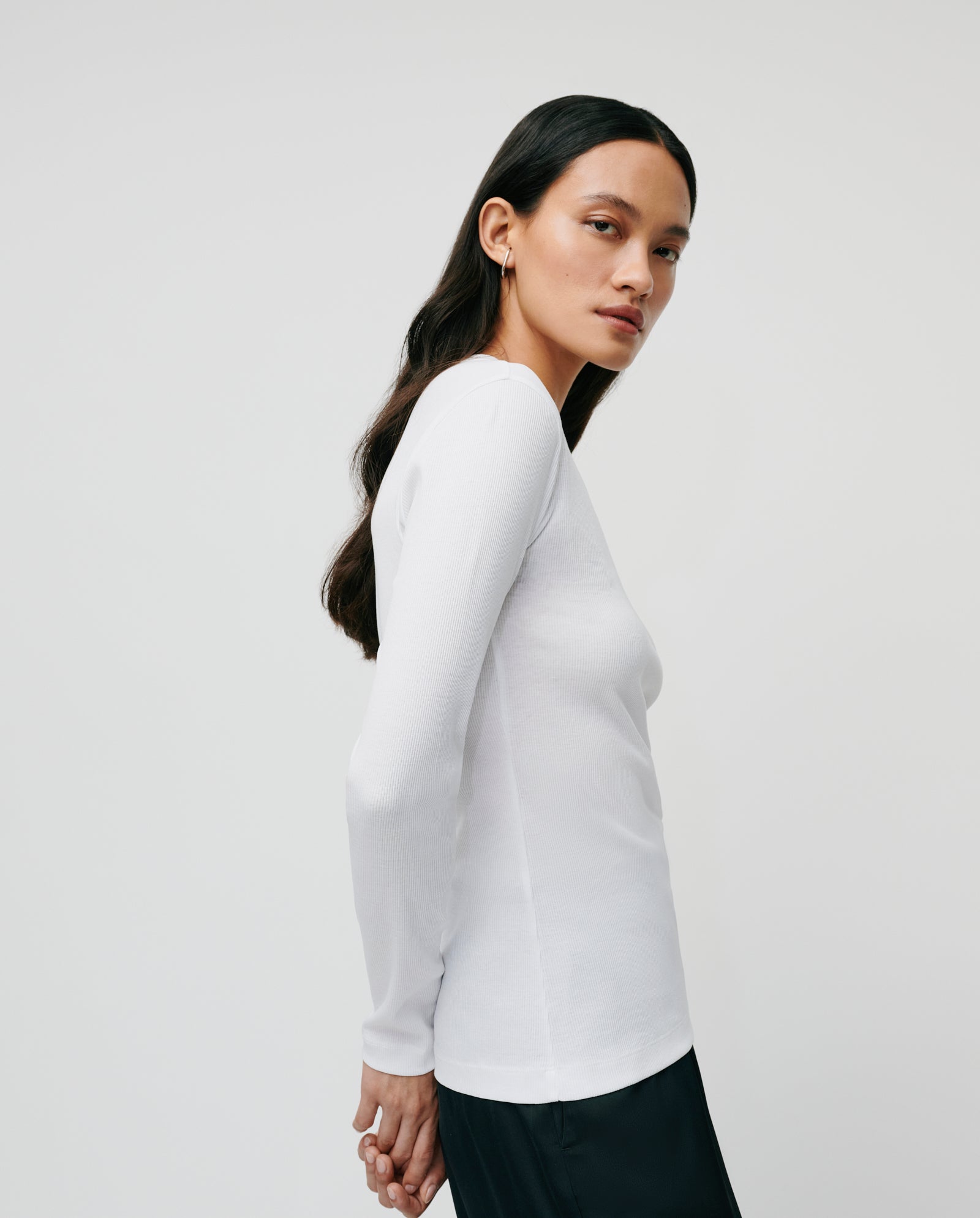 A woman with long dark hair wears a comfortable IVY OAK KOLLINA Top made from organic cotton and black pants, standing against a plain background.