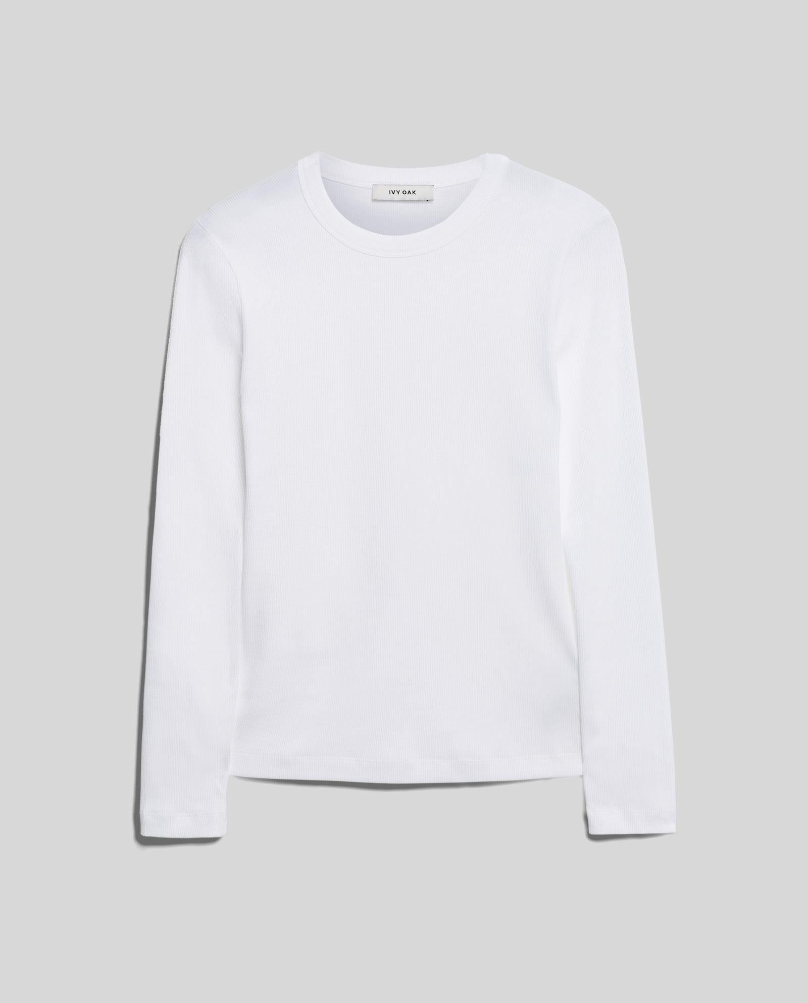 The IVY OAK KOLLINA Top is a plain white long-sleeve crew neck made from organic cotton for comfort, shown on a light gray background.
