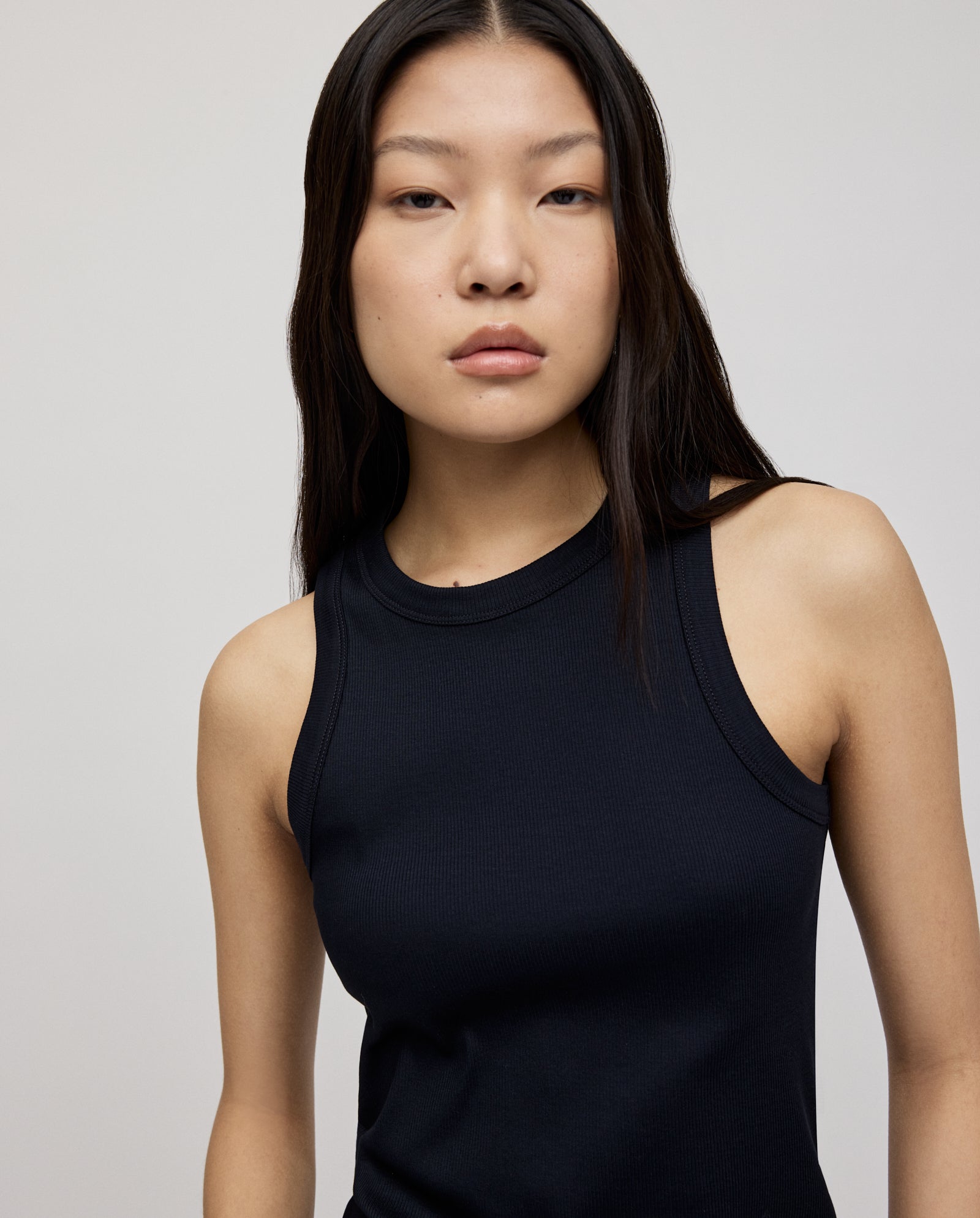 A woman with long dark hair wears the KLARA ANN Top by IVY OAK, made from comfortable organic cotton, standing against a plain background.