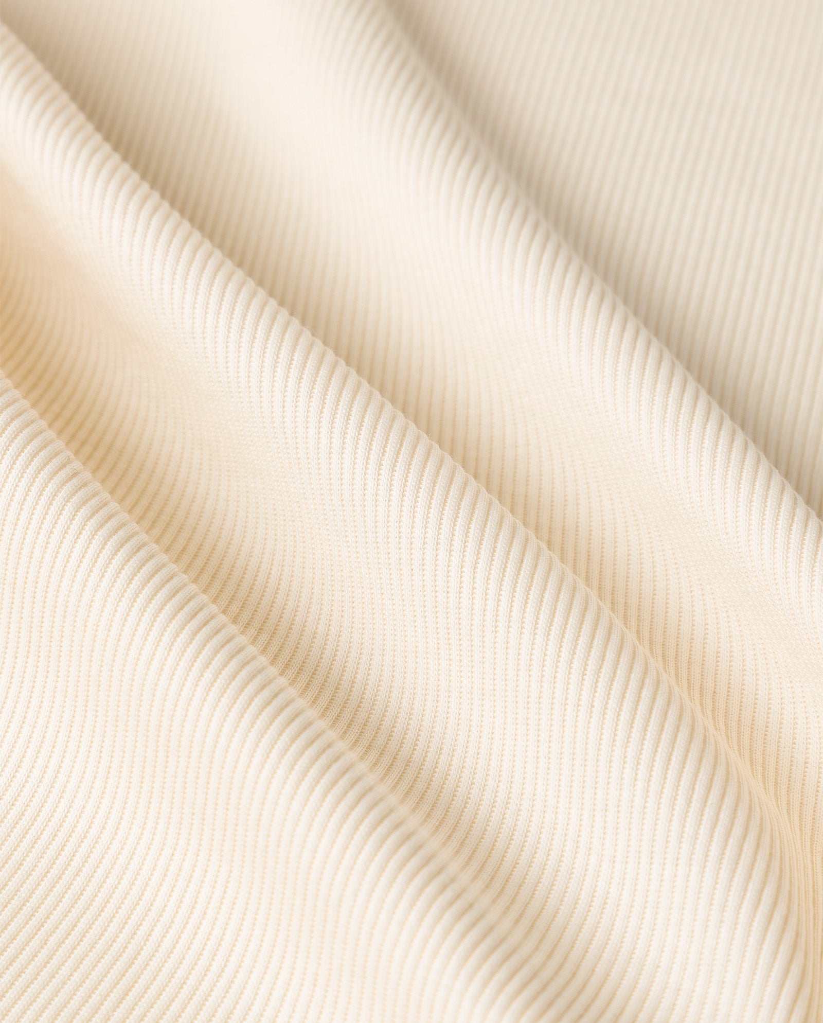 Close-up of the KLARA ANN Top by IVY OAK, featuring cream-colored ribbed organic cotton fabric with soft folds and a textured surface, perfect for comfort.