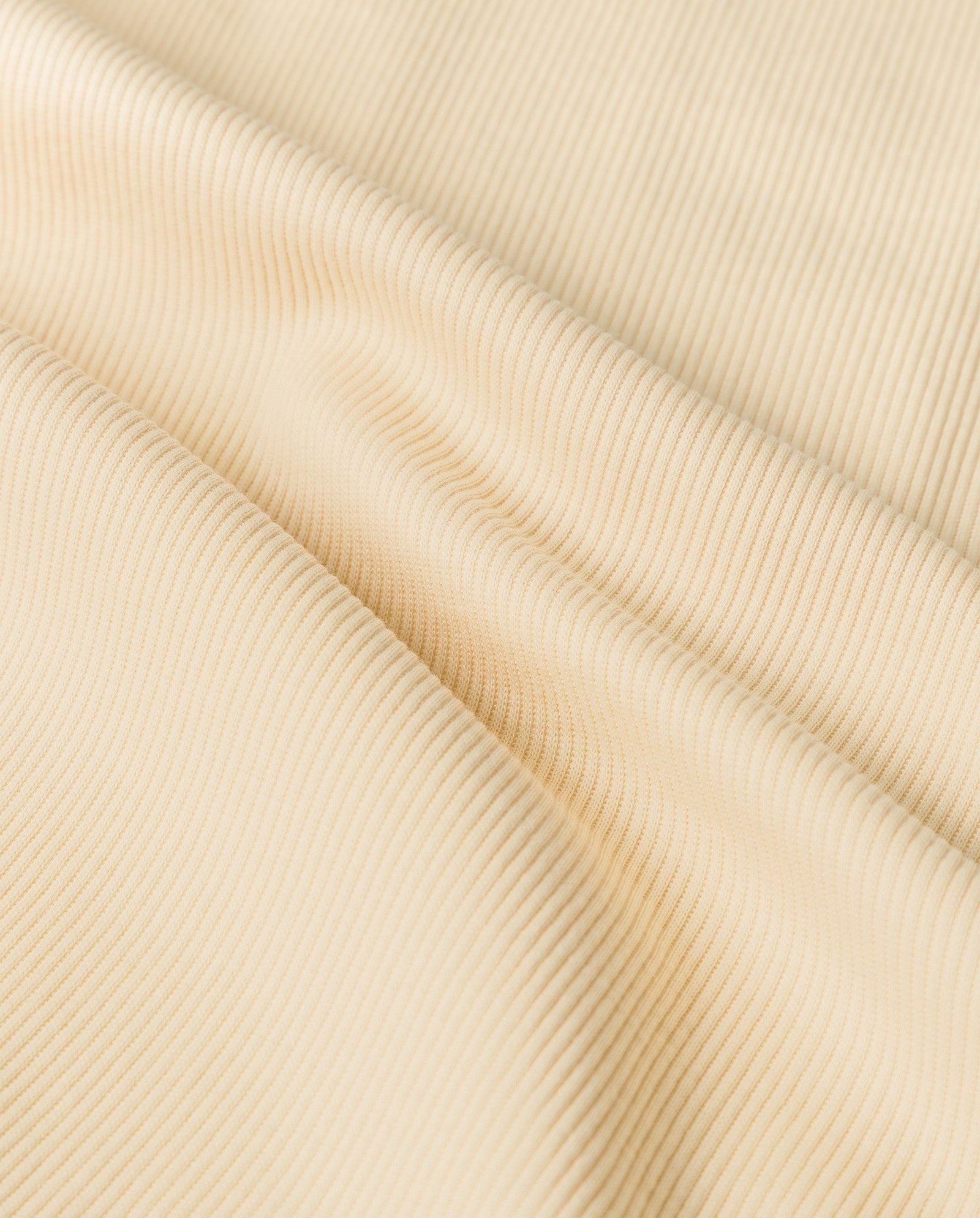 Close-up of the KLARA ANN Top by IVY OAK, featuring comfortable, cream-colored ribbed fabric made from Organic Cotton, with soft folds and textured, evenly spaced vertical lines.