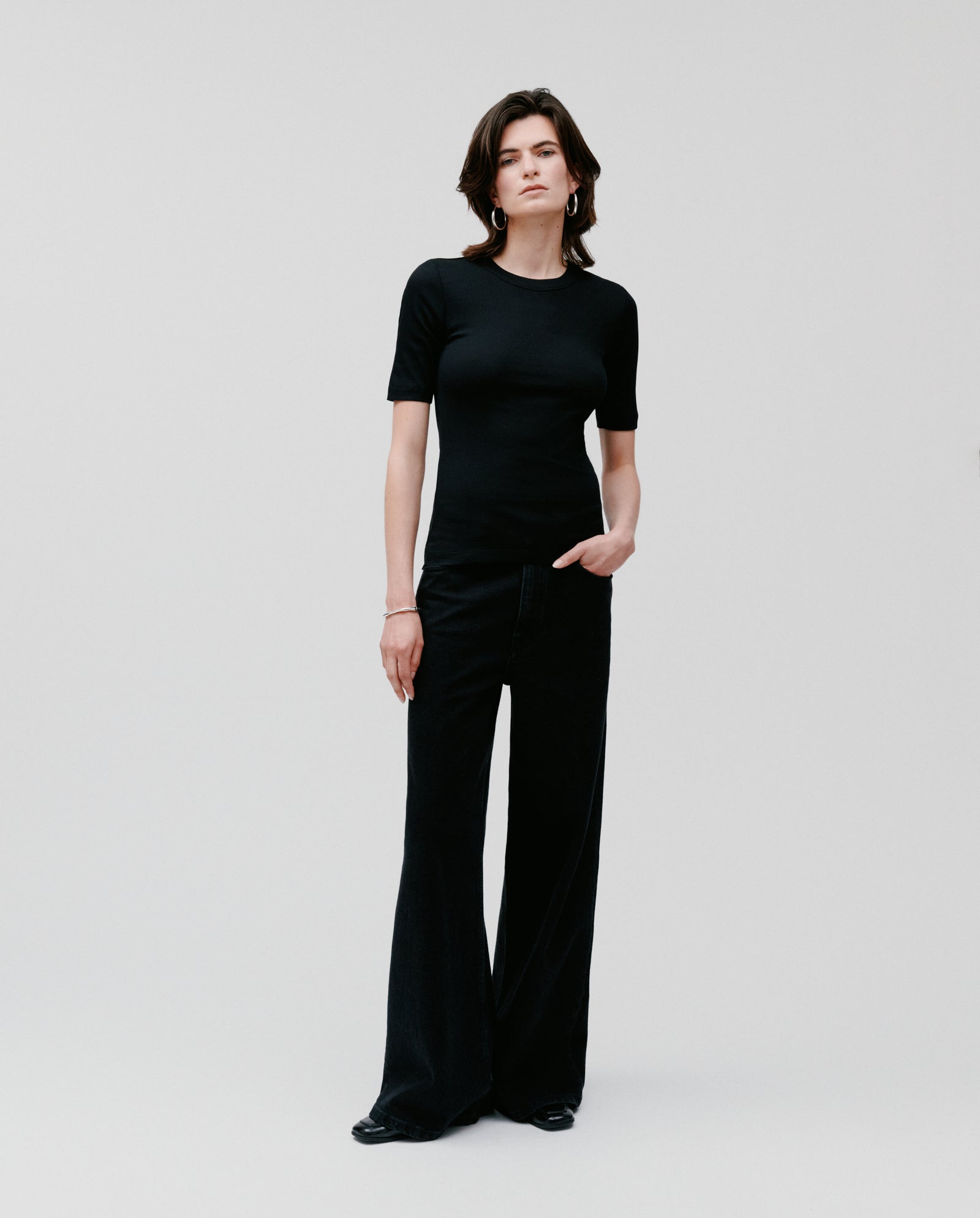 A person in a comfortable black IVY OAK KRISTIN Top and wide-leg pants stands against a plain light background.