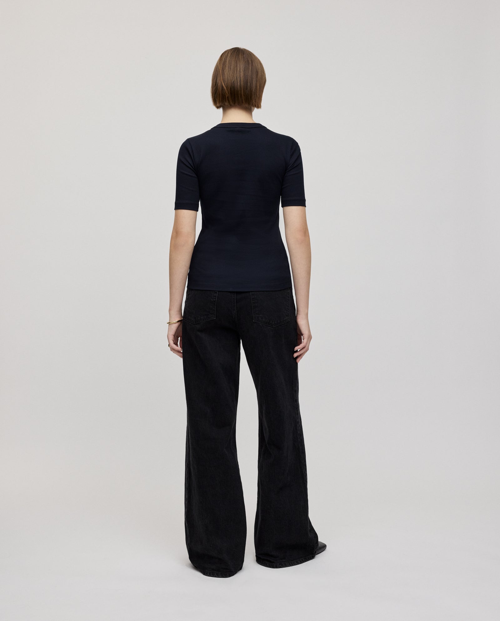 Person with short hair, wearing the IVY OAK KRISTIN Top in black and matching pants, standing facing away.