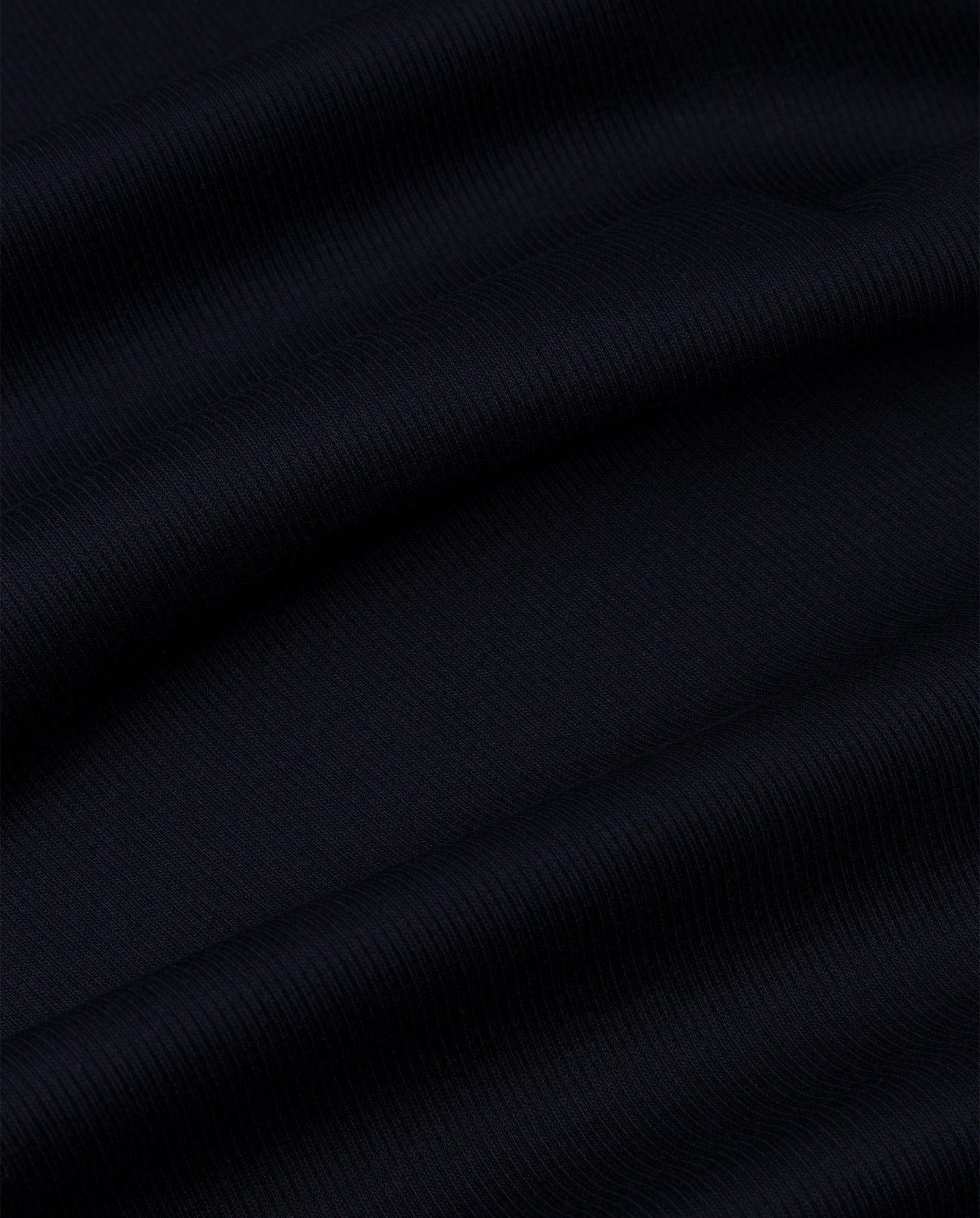 Close-up of the KRISTIN Top by IVY OAK in black ribbed fabric, highlighting its soft horizontal folds and subtle texture—crafted from comfortable organic cotton for a perfect everyday piece.