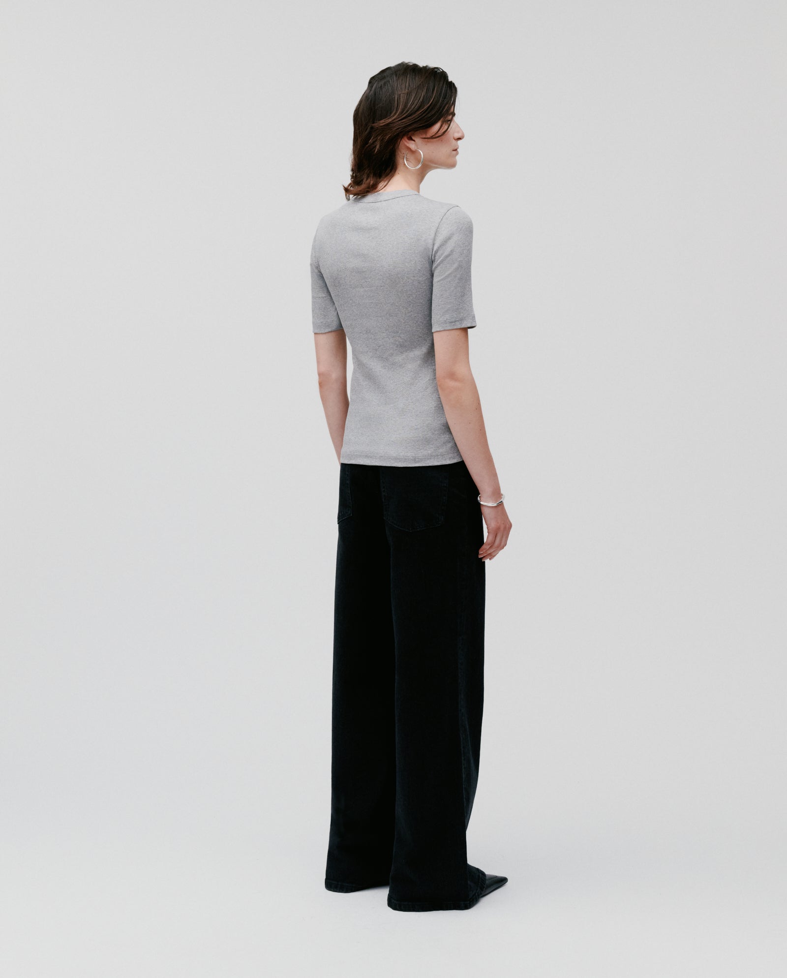 A person stands facing away, wearing a comfortable IVY OAK KRISTIN Top and gray and black wide-leg pants made from soft organic cotton, against a plain background.