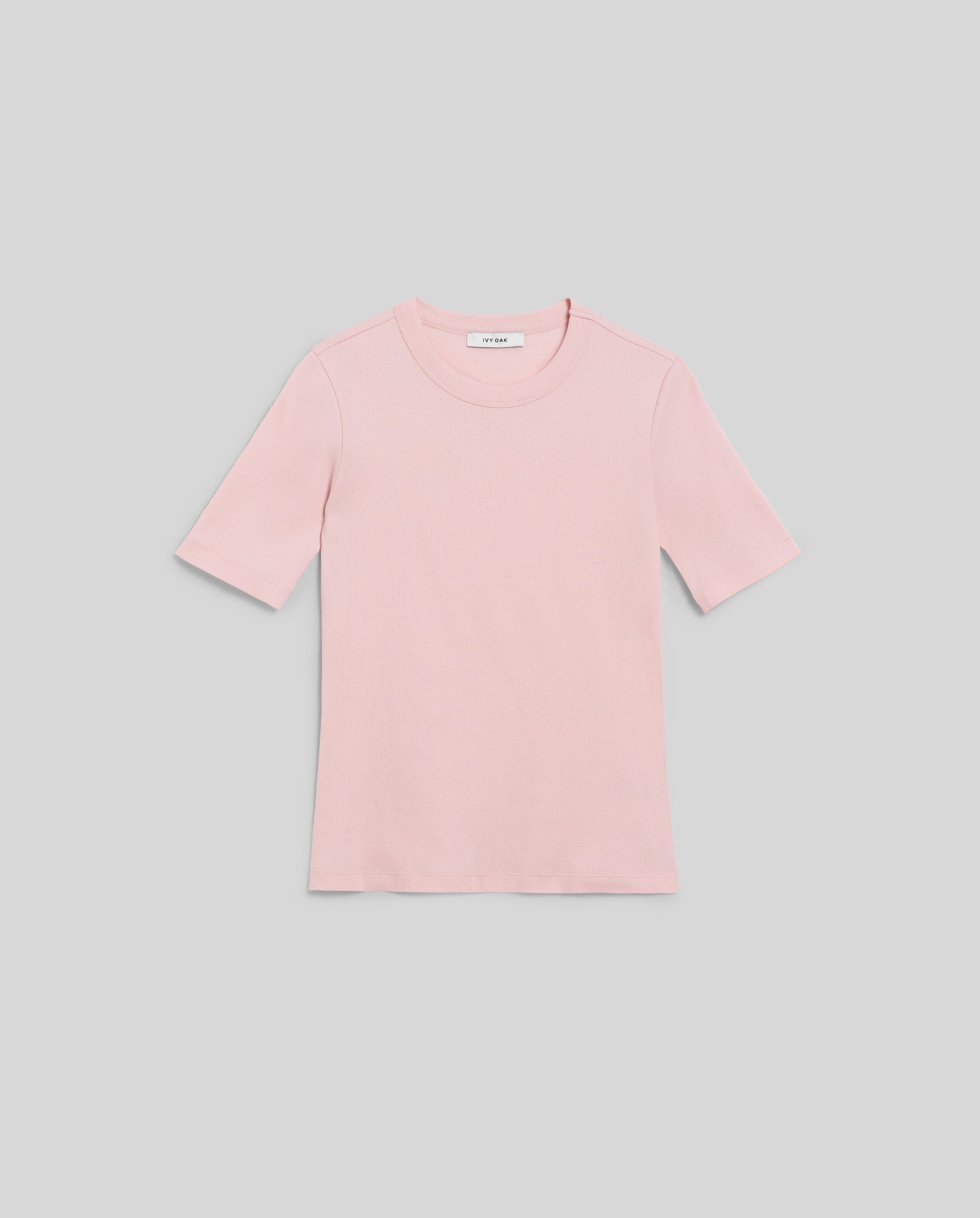 A KRISTIN Top by IVY OAK in plain light pink, crafted from comfortable organic cotton, is laid flat on a light gray background.