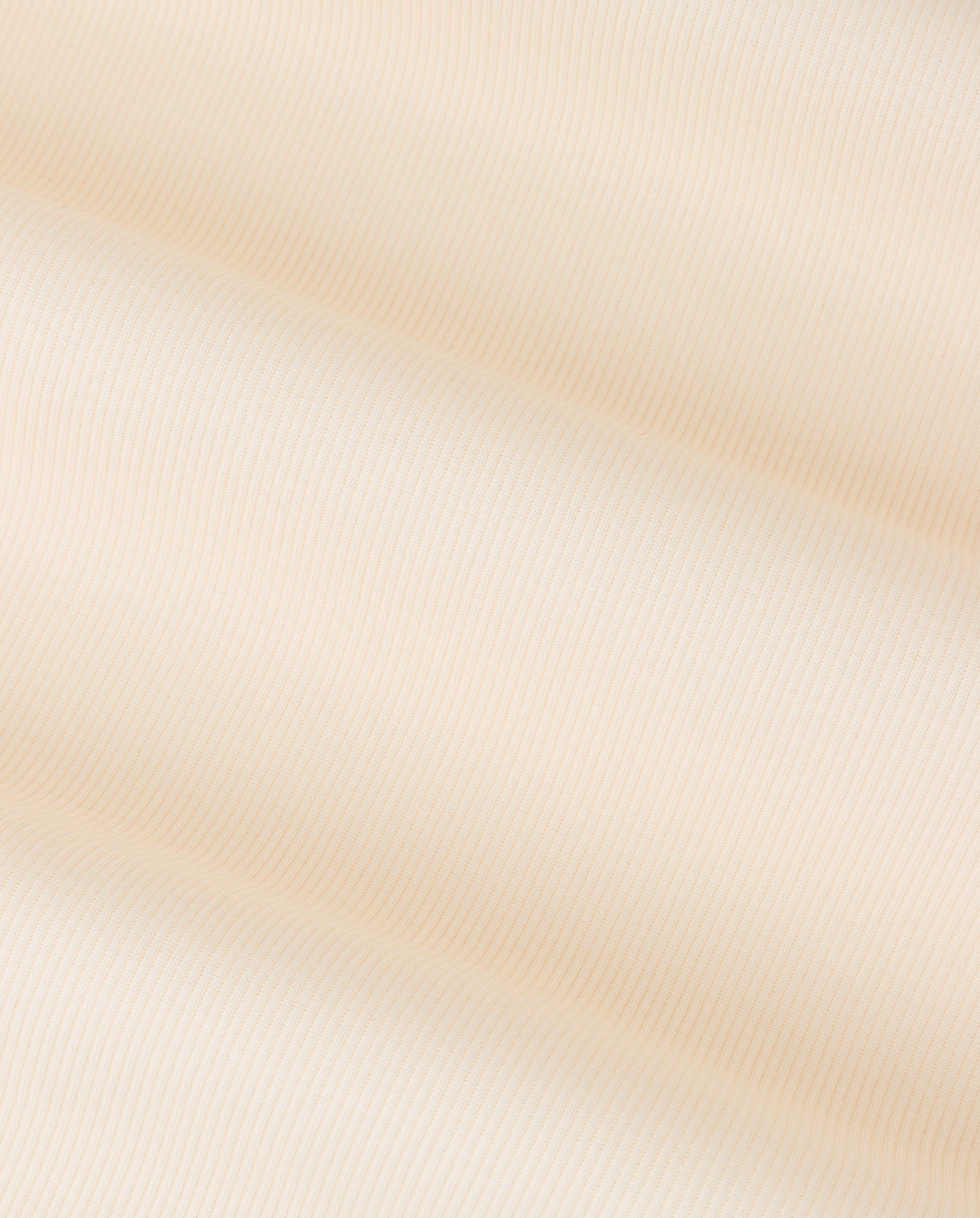 Close-up of soft, beige fabric with subtle diagonal stripes and gentle folds, showcasing the comfort of Organic Cotton in the KRISTIN Top by IVY OAK.