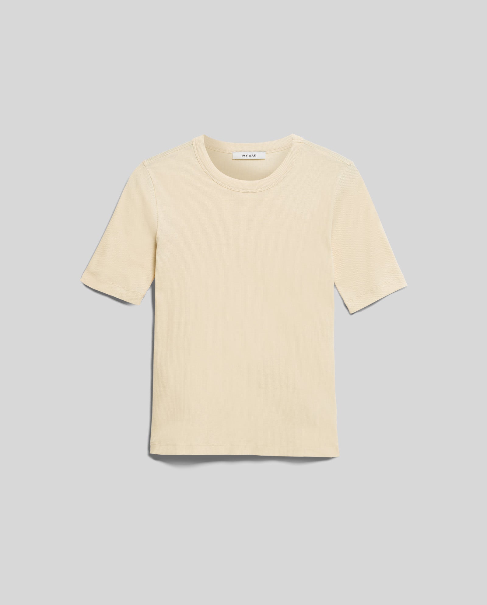 The KRISTIN Top by IVY OAK, a beige short-sleeve tee crafted from organic cotton, is shown laid flat on a light gray background for an effortlessly casual style.