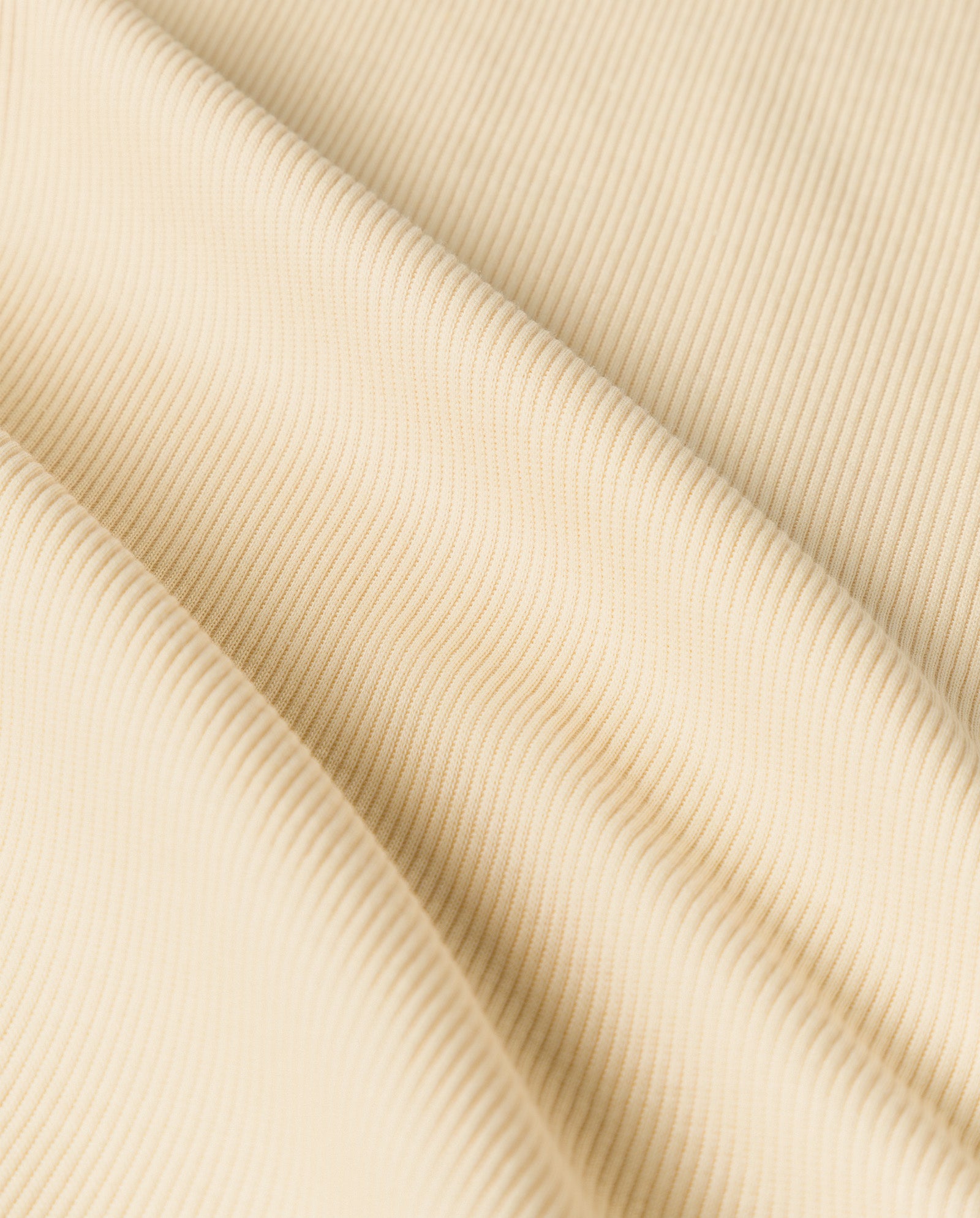 Close-up of cream-colored ribbed fabric with diagonal folds and soft texture, highlighting the comfort of Organic Cotton in the IVY OAK KRISTIN Top.