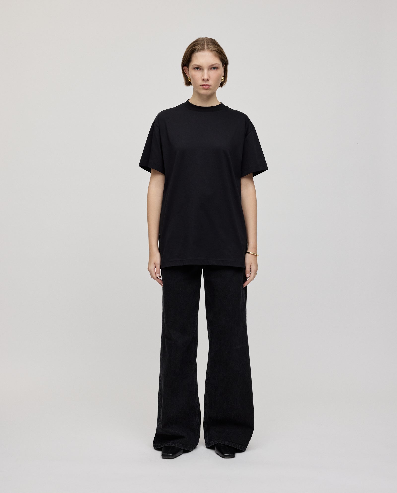 A person stands facing forward, wearing the KYLA ROSE Top by IVY OAK and wide-leg black pants against a plain background—a versatile look for any wardrobe.