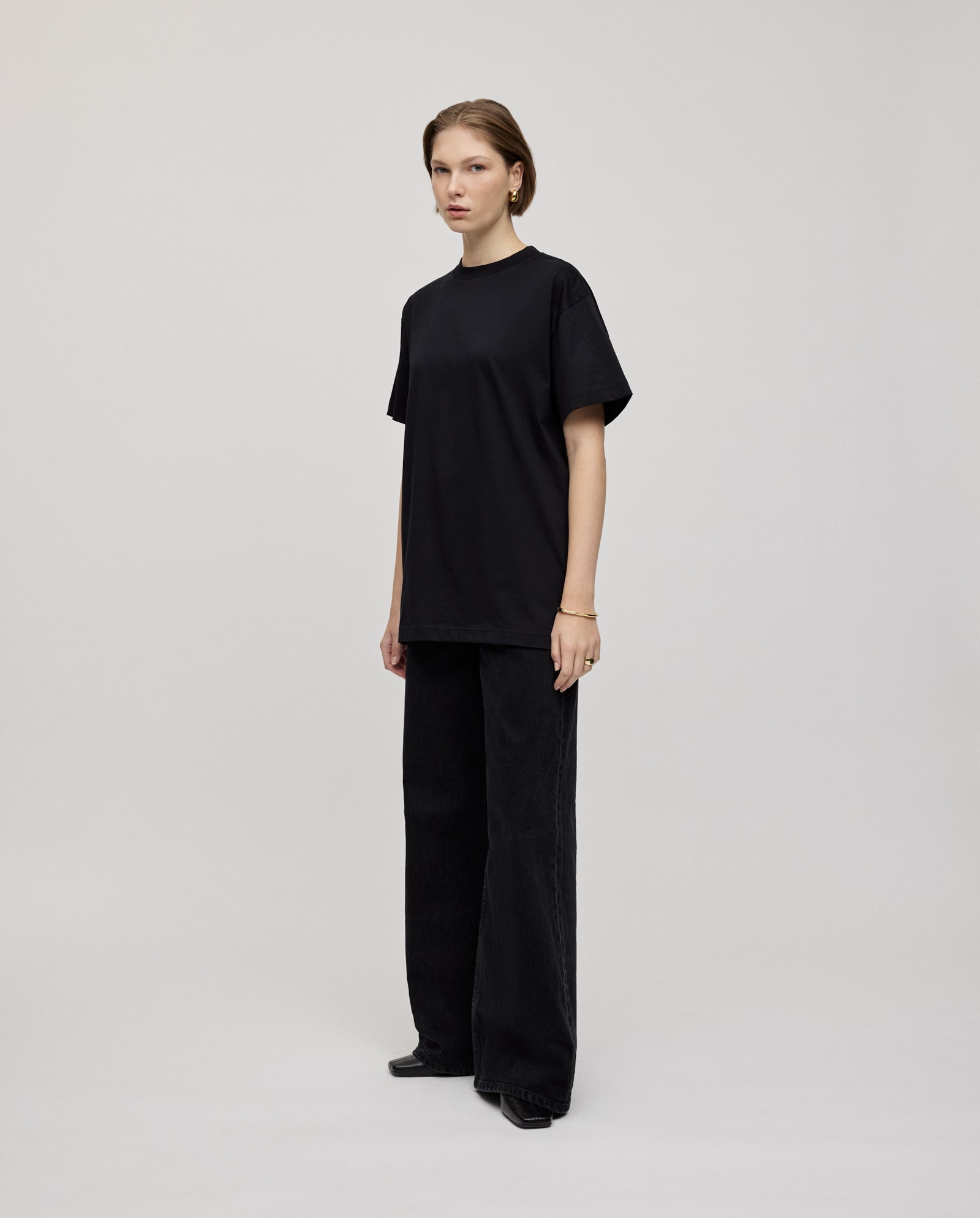 In a minimalist studio, a person wears the IVY OAK KYLA ROSE Top—an ultra-soft, boxy T-shirt that’s an effortlessly stylish staple for any wardrobe.