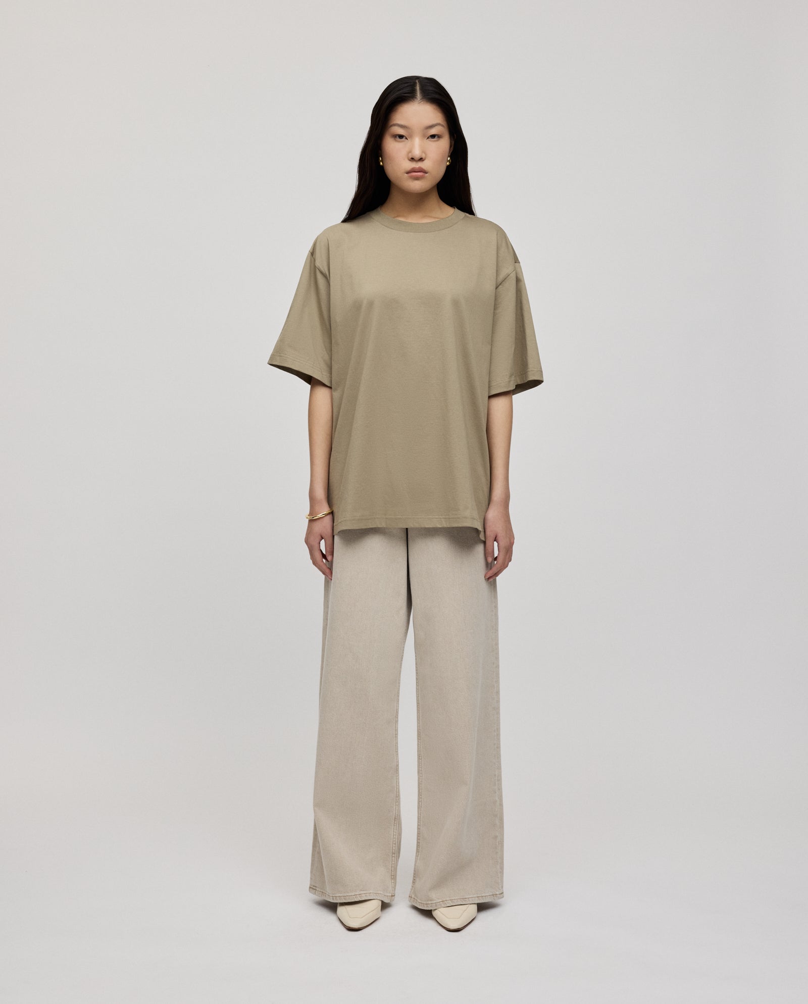 A woman wears the IVY OAK KYLA ROSE Top in beige, styled with loose wide-leg light pants, standing against a plain light background.