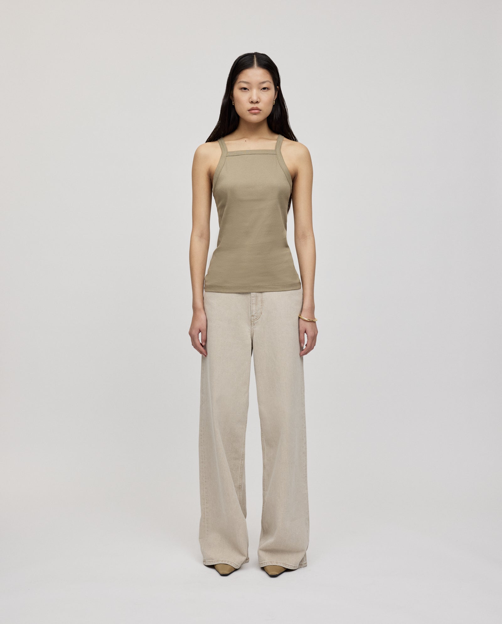 A woman with narrow shoulders faces forward wearing the IVY OAK KLARA ROSE Top, a taupe tank top, and wide-leg beige pants against a plain background.