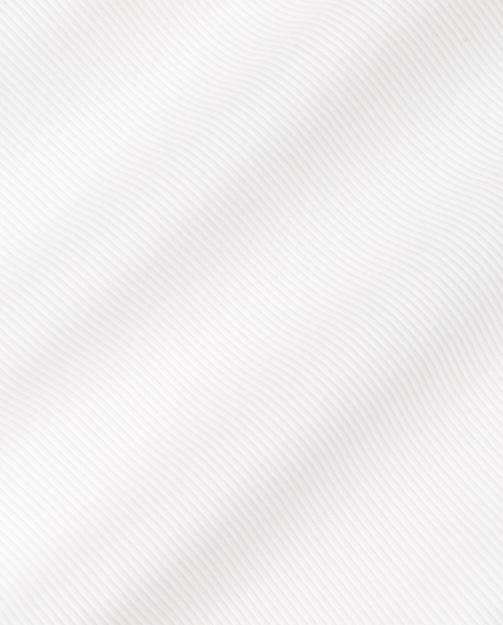 Close-up of the KLARA ROSE Top by IVY OAK, featuring white textured fabric with narrow shoulders and a rippled optic, displaying subtle diagonal ridges and soft waves across the surface.