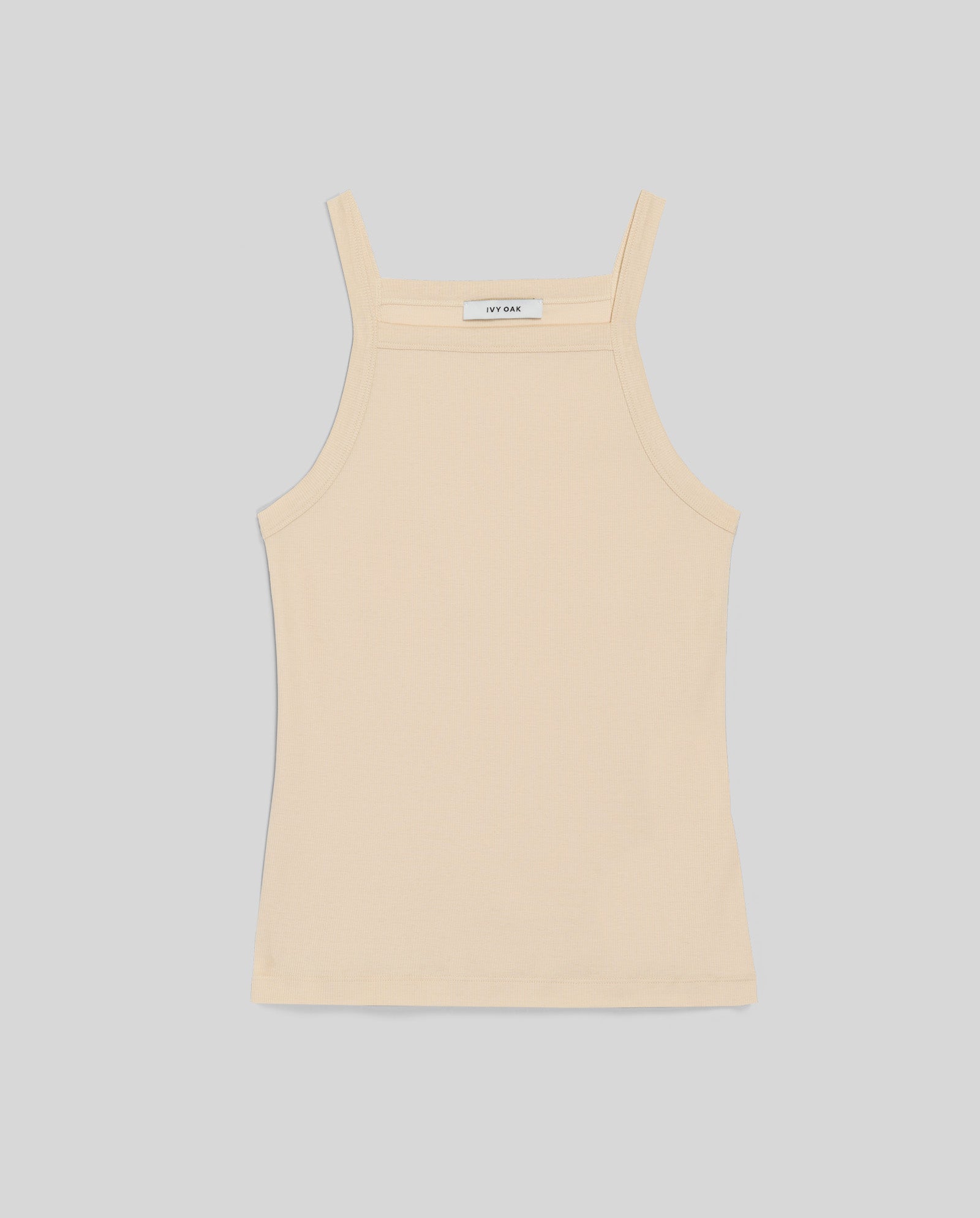 The IVY OAK KLARA ROSE Top is a beige ribbed spaghetti strap tank with a straight neckline, designed to accentuate the shoulders, shown laid flat on a light gray background.
