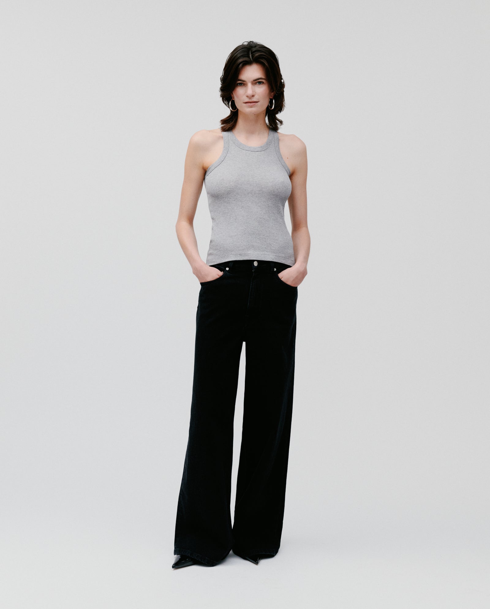 A woman wearing the IVY OAK FINLEY Top and black wide-leg pants stands with her hands in her pockets against a plain background.