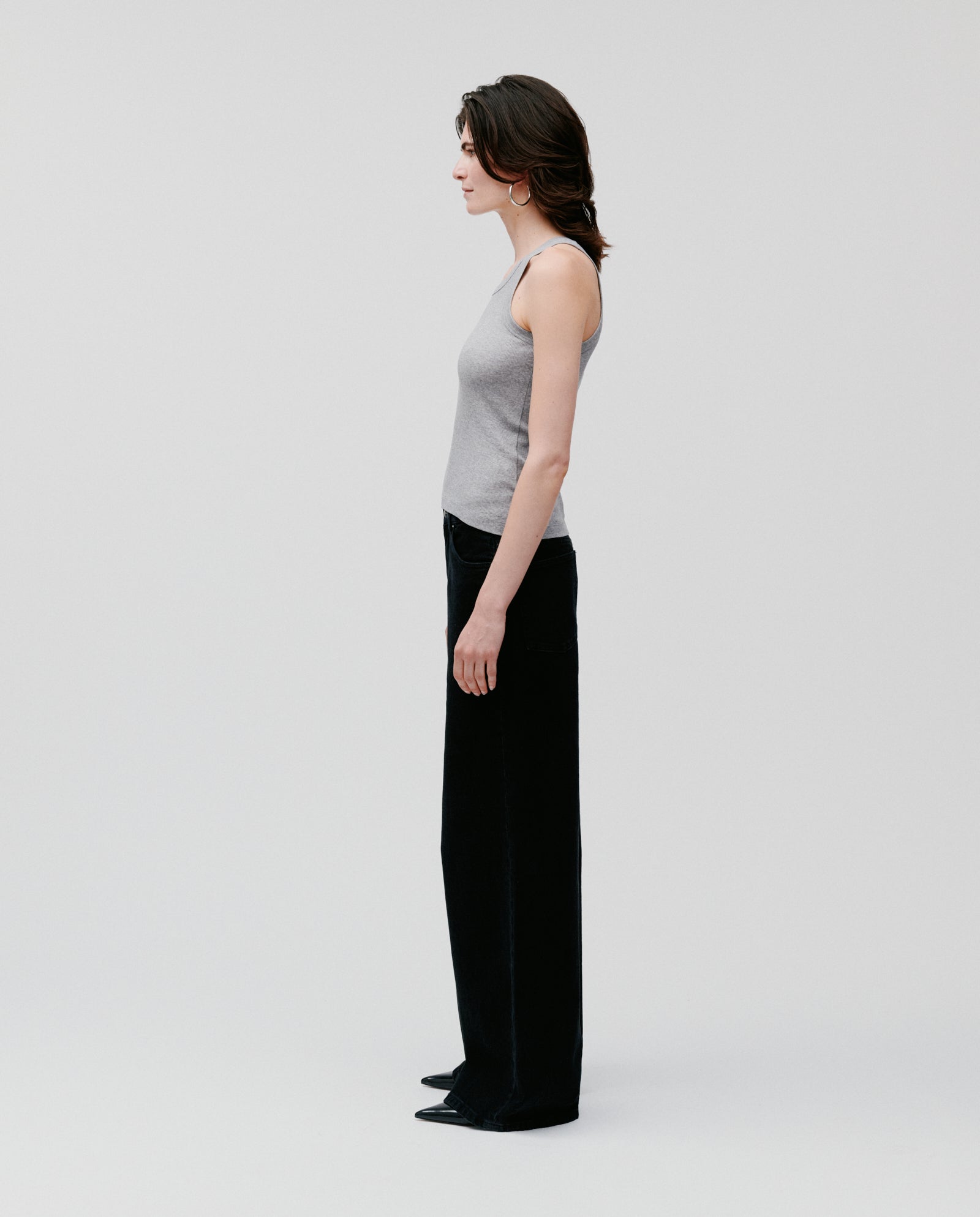 A woman in profile wears the IVY OAK FINLEY Top in gray with black pants, set against a plain white background.