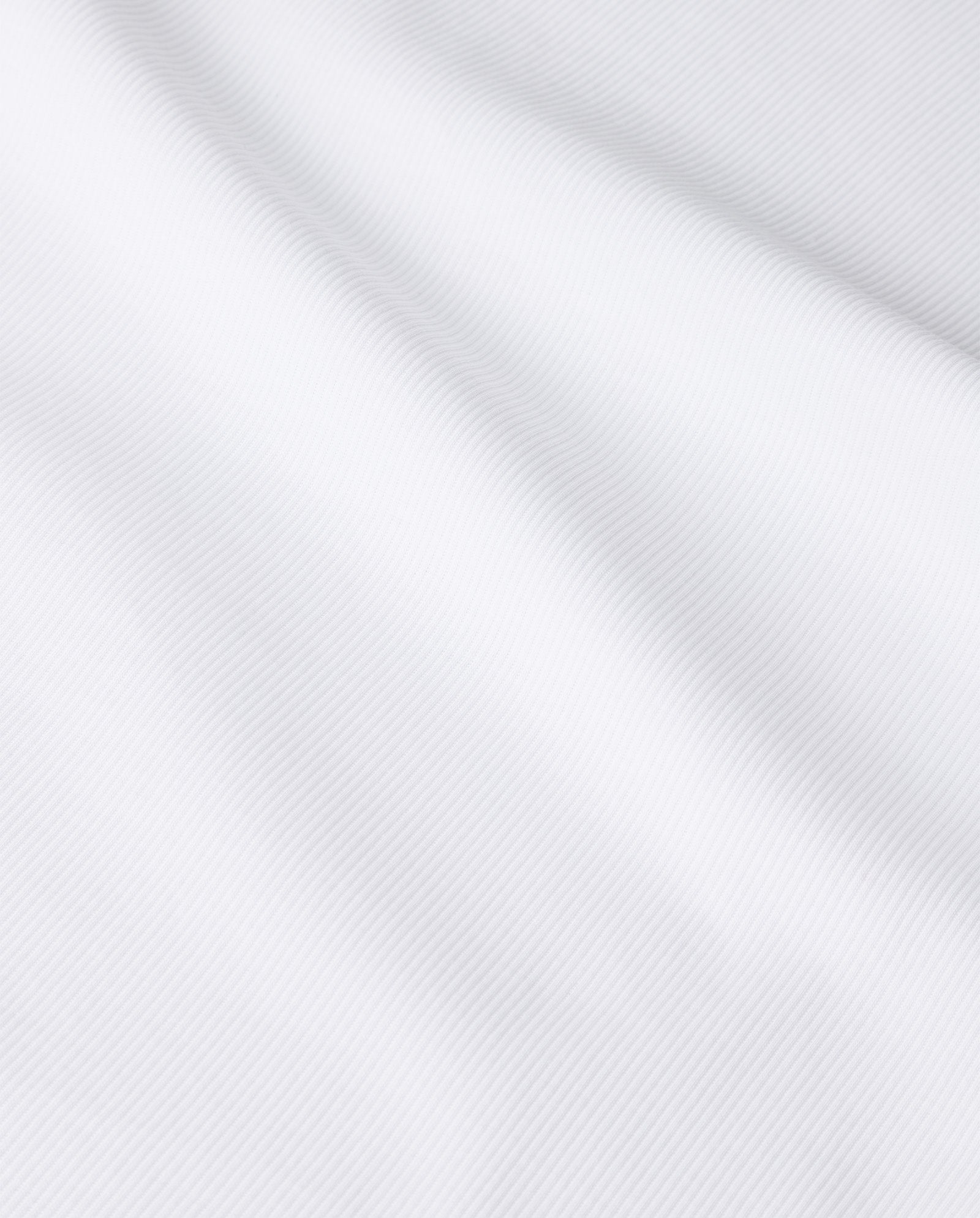 Close-up of the FINLEY Top by IVY OAK, a womens white sleeveless top with subtle diagonal lines and gentle folds accentuating its smooth, fine knit texture.