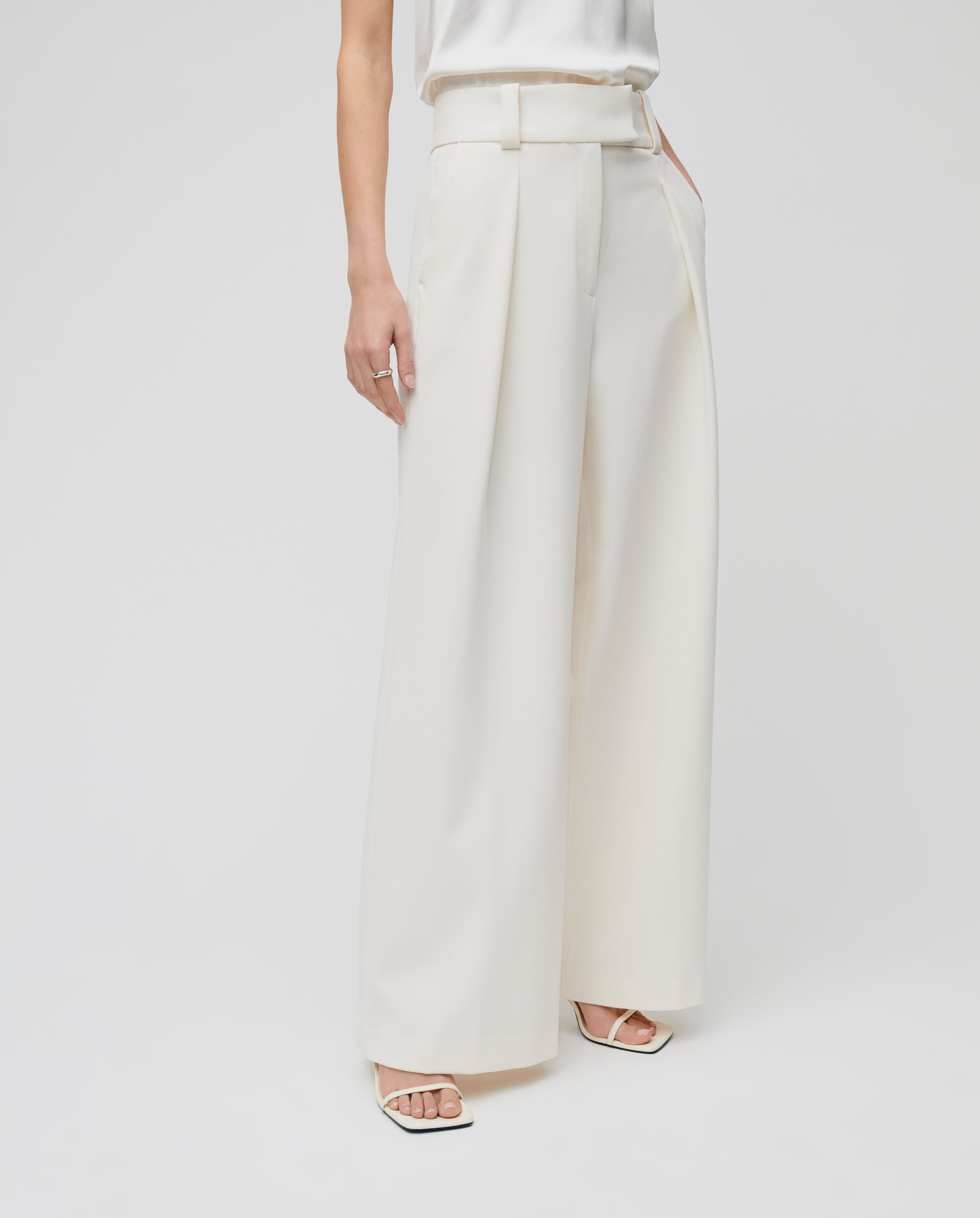 Model wears the PEONY ROSE Trouser by IVY OAK, featuring a high waist, wide legs, and a belt; styled with square-toe sandals on a white background.