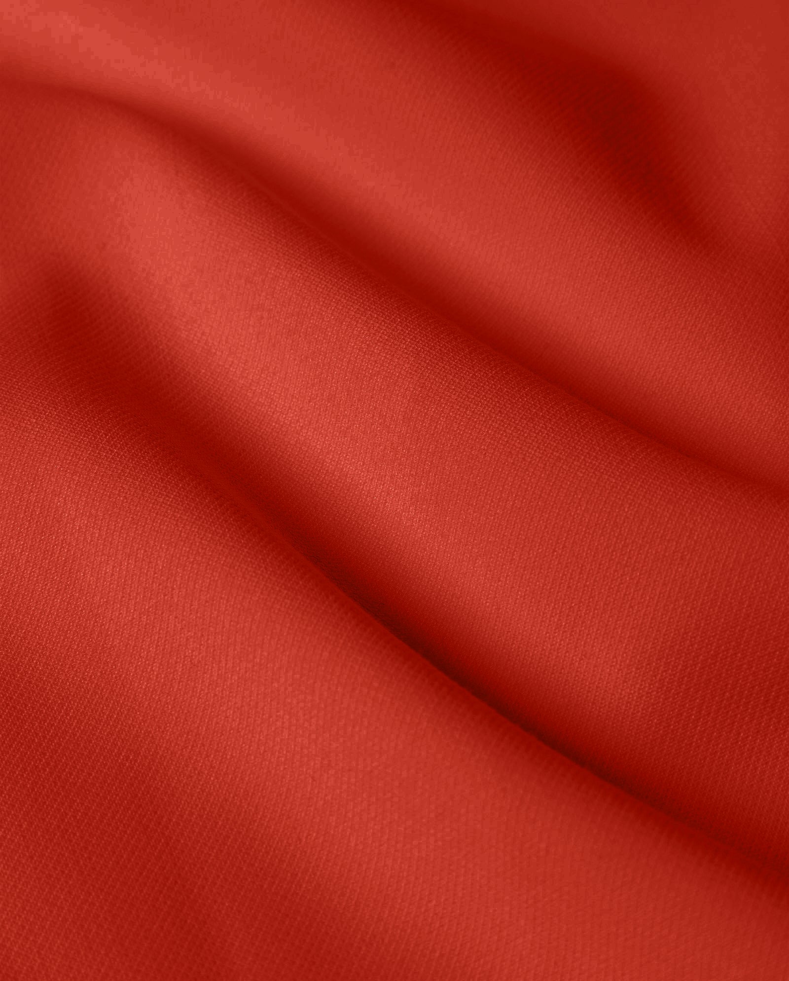 Close-up of smooth red fabric with gentle folds and soft shadows, reflecting the elegant drape and body-hugging fit of the IVY OAK NOLAN Dress.