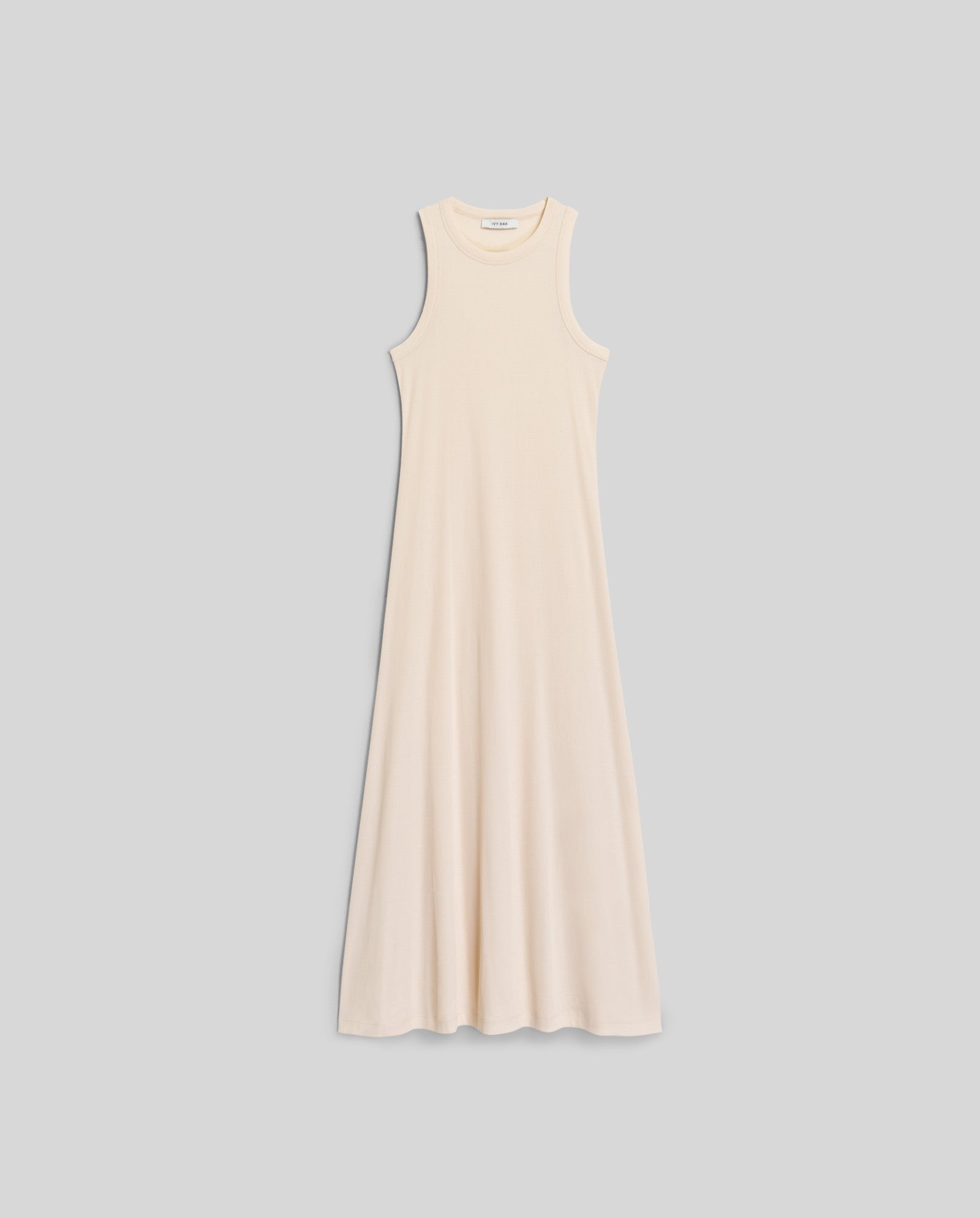 The IVY OAK KRISTYNA Dress is a sleeveless, cream-colored ribbed knit maxi with a flared skirt, displayed flat on a light gray background.