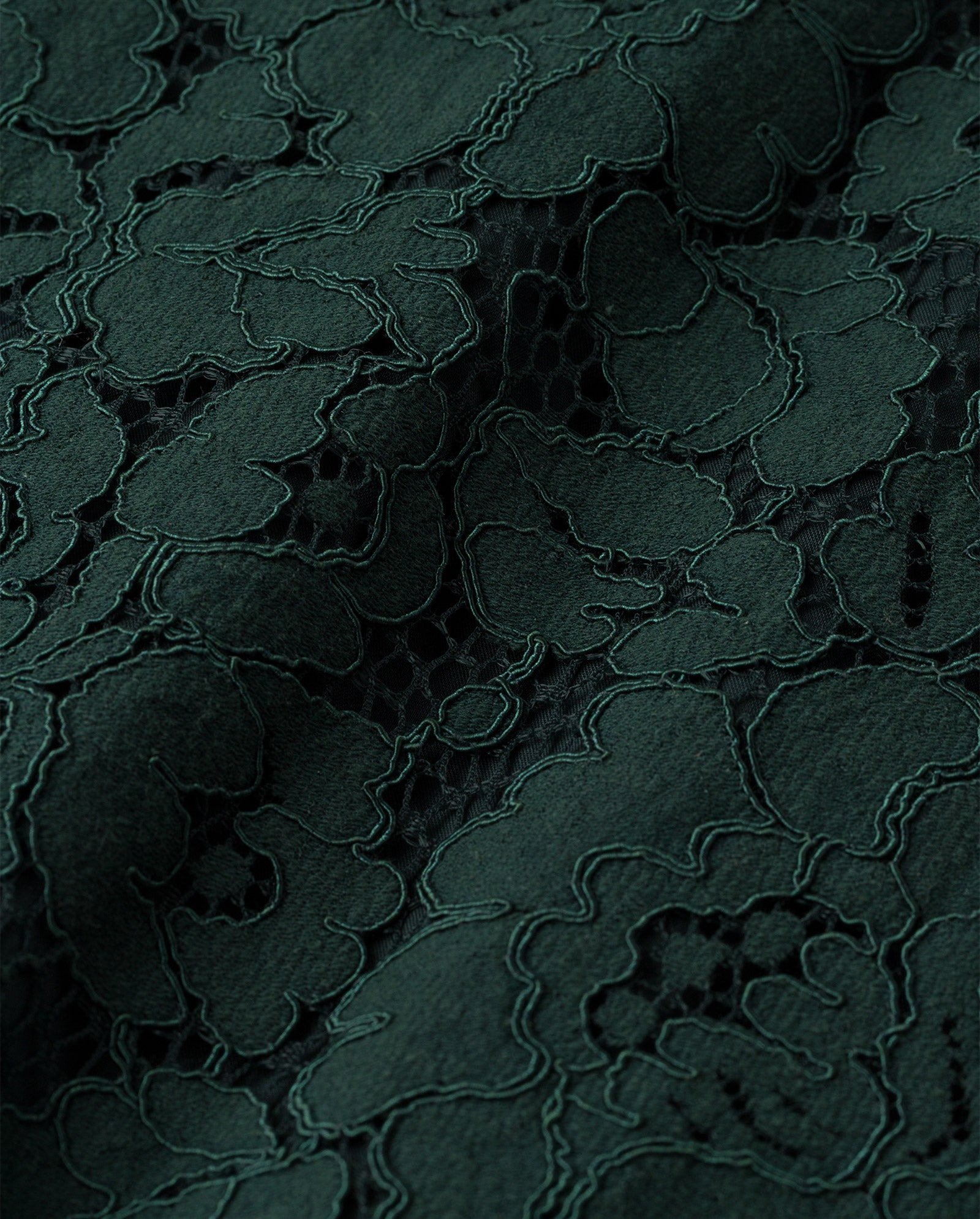 Close-up of dark green floral lace fabric from the MADELEINE Dress by IVY OAK, showing its intricate, delicate patterns and rich texture—ideal for designs with V-neck or elegant back detail.