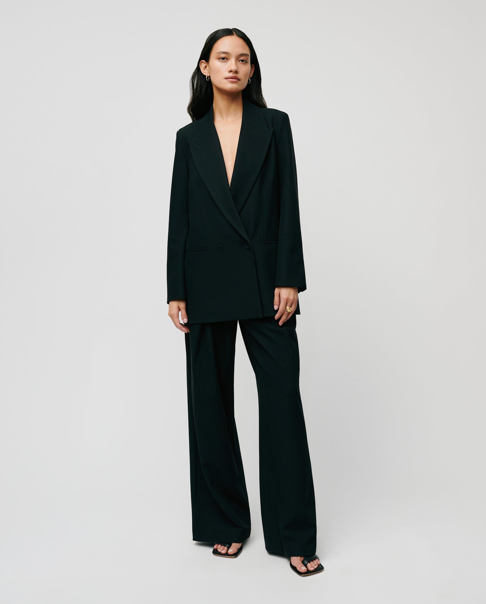 A woman wears the IVY OAK JIL Blazer, featuring a black peak lapel, open front, and wide-leg pants, standing against a plain light background.