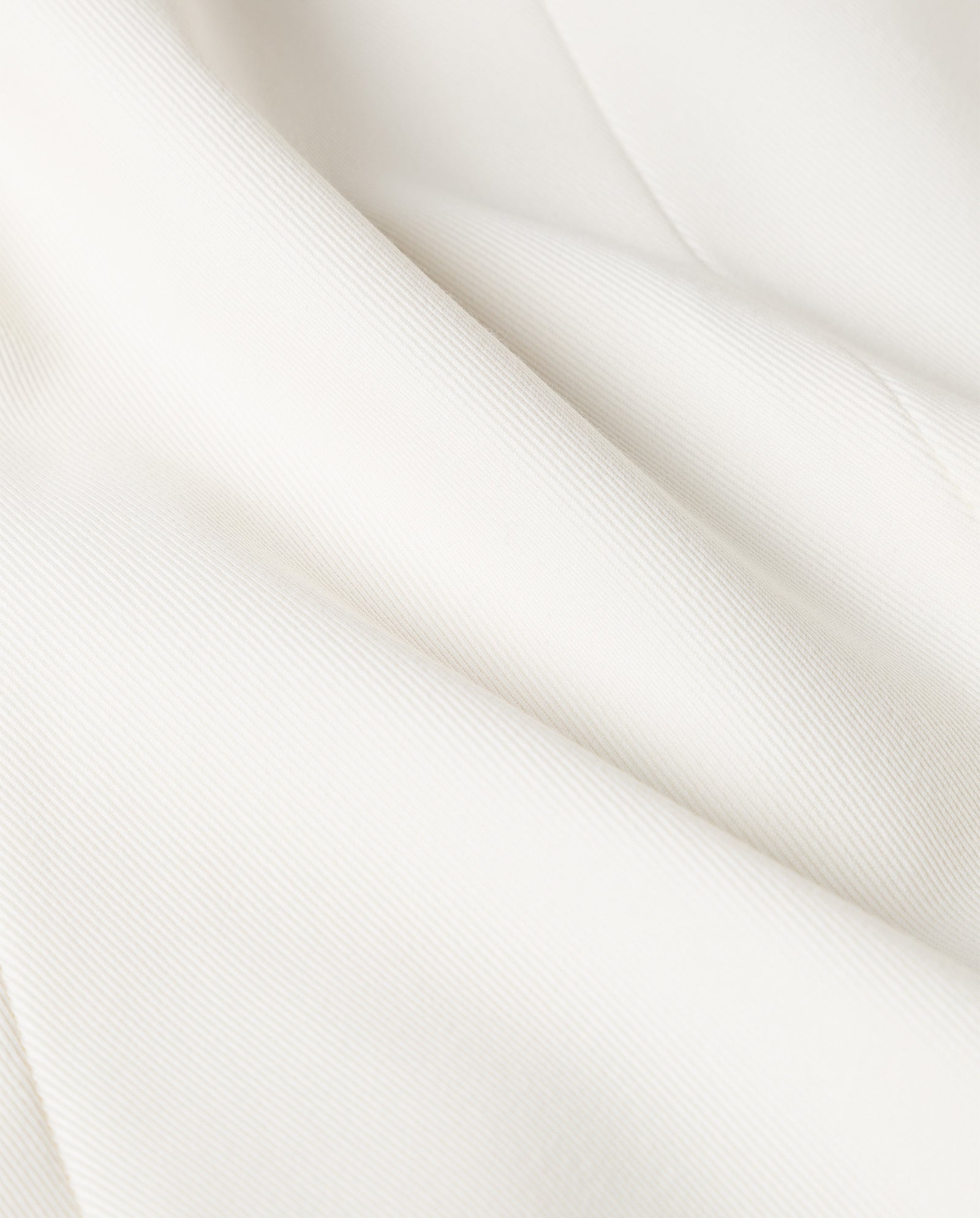 Close-up of the soft, white fabric with subtle texture and gentle folds—ideal for creating the JIL Blazer by IVY OAK, a refined double-breasted Tuxedo blazer.