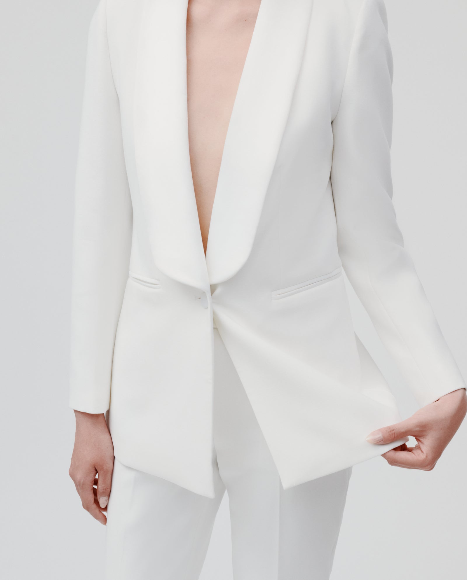 Model wears the IVY OAK JANA Blazer, featuring a shawl collar and lined interior, styled shirtless and holding one side open against a plain background.