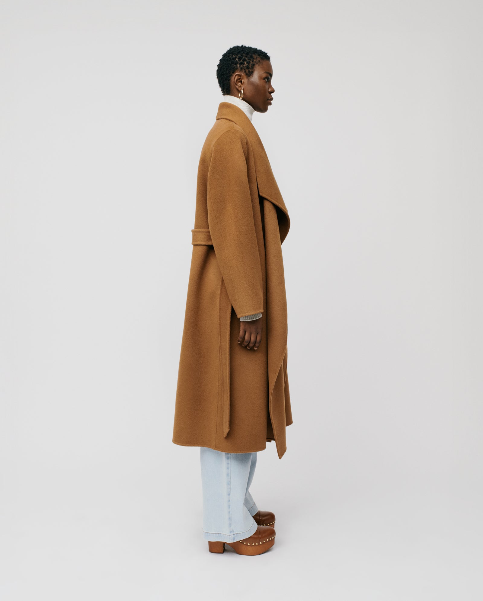 A person in the IVY OAK CARRIE ROSE coat with a big lapel collar, light jeans, and clogs stands sideways against a plain background.