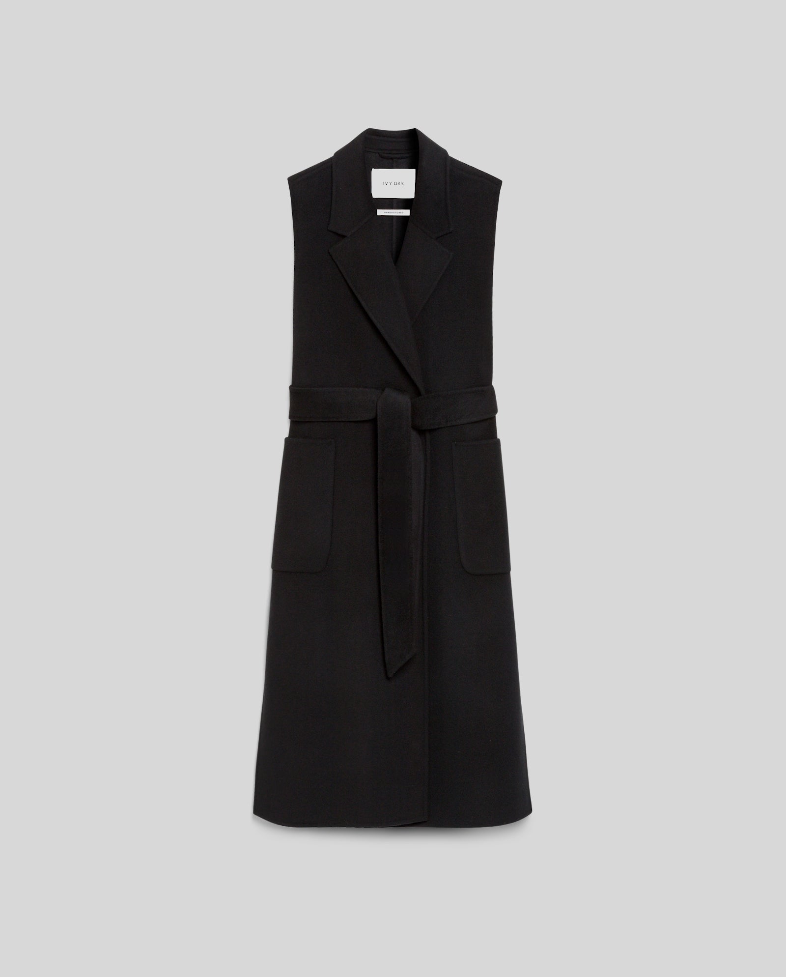 The CLARISSA Vest by IVY OAK (DE) is a sleeveless black design with a lapel collar and large front pockets, made from RWS wool, shown on a gray background.