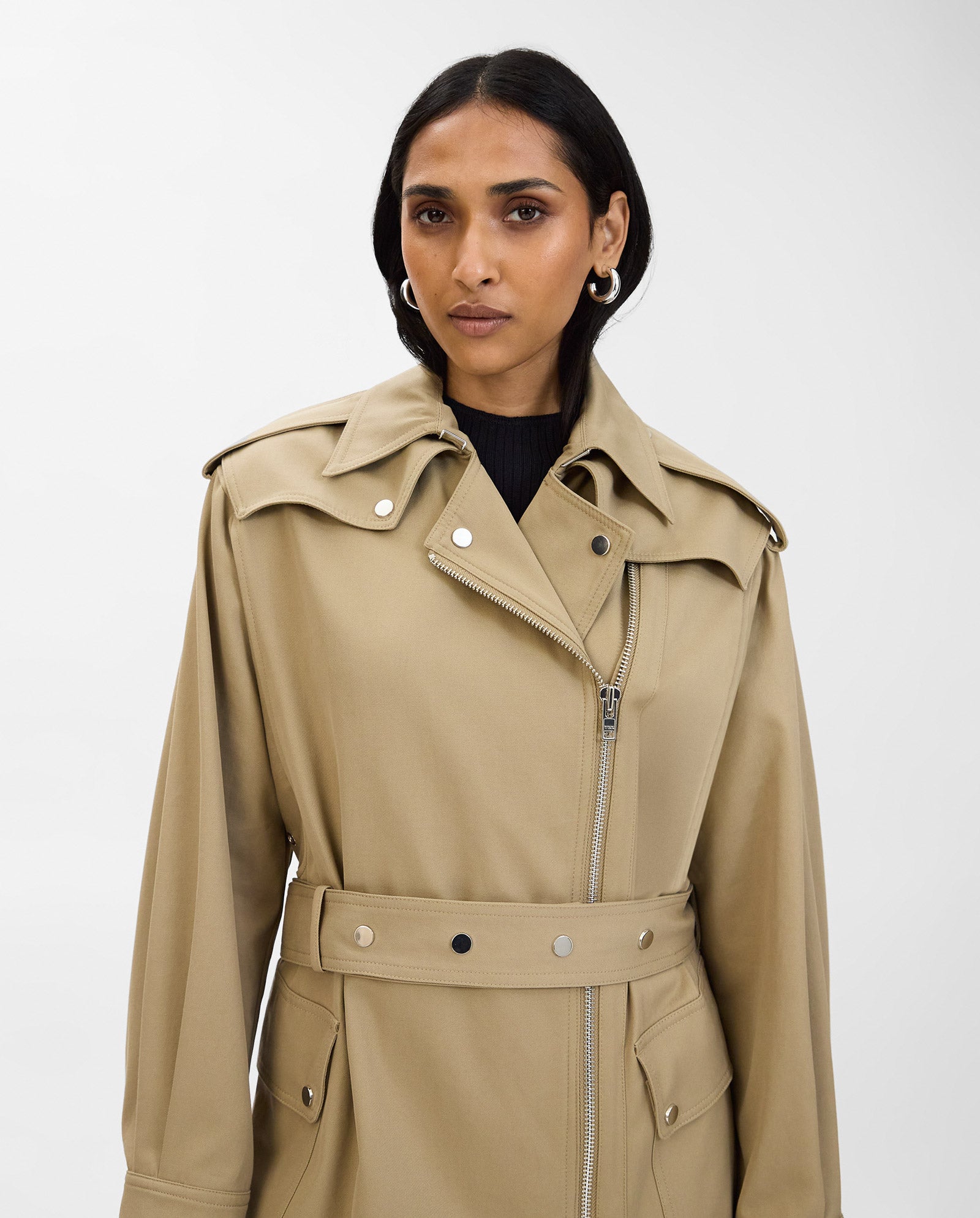 A woman models the IVY OAK CIARA Coat, an oversized beige trench coat with an adjustable belt and button details, set against a plain white background.