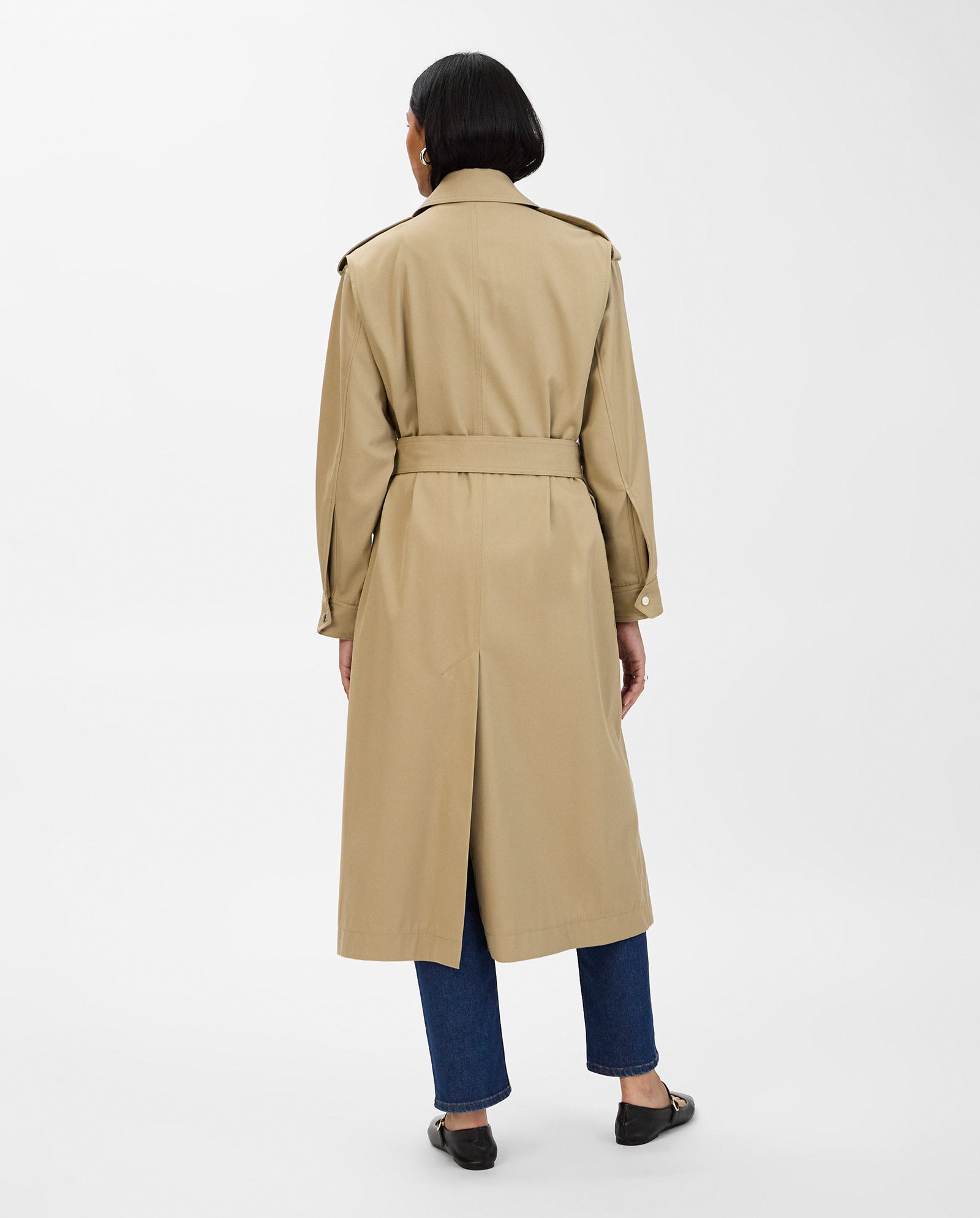 A person wearing the IVY OAK CIARA Coat with an adjustable belt, styled with blue jeans and black shoes, stands with their back to the camera.