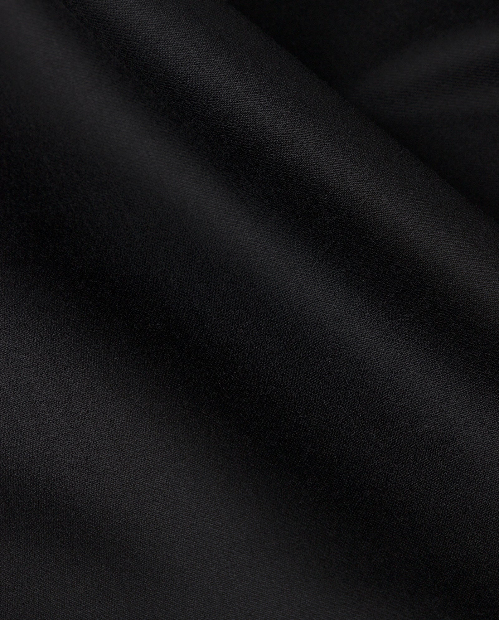 The COLETTE Coat by IVY OAK features smooth black satin fabric with soft folds and a subtle sheen, ideal for an oversized trench coat look.