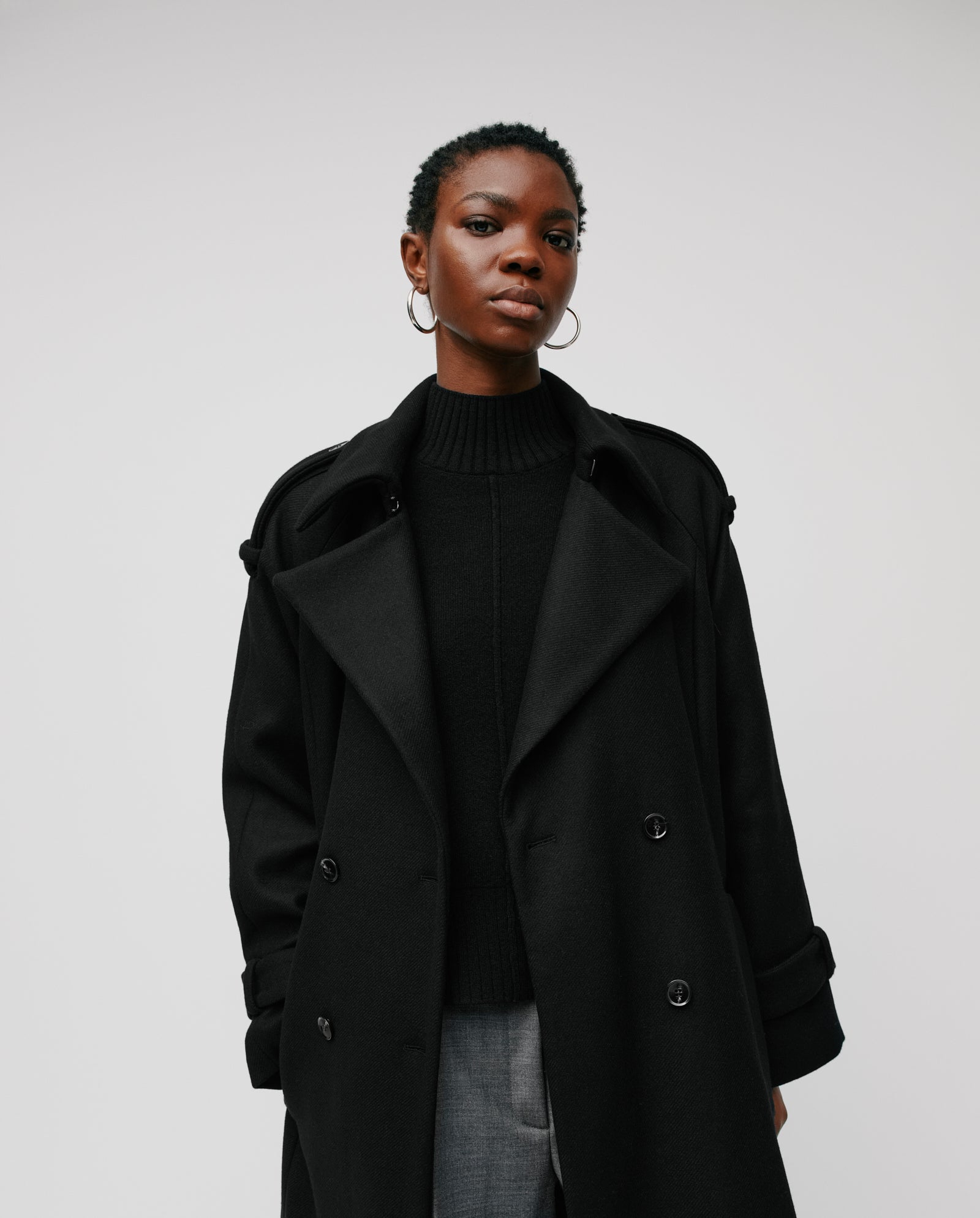 A person models the IVY OAK CAROLINE ANN Coat, paired with a sweater, confidently facing the camera against a plain white background.