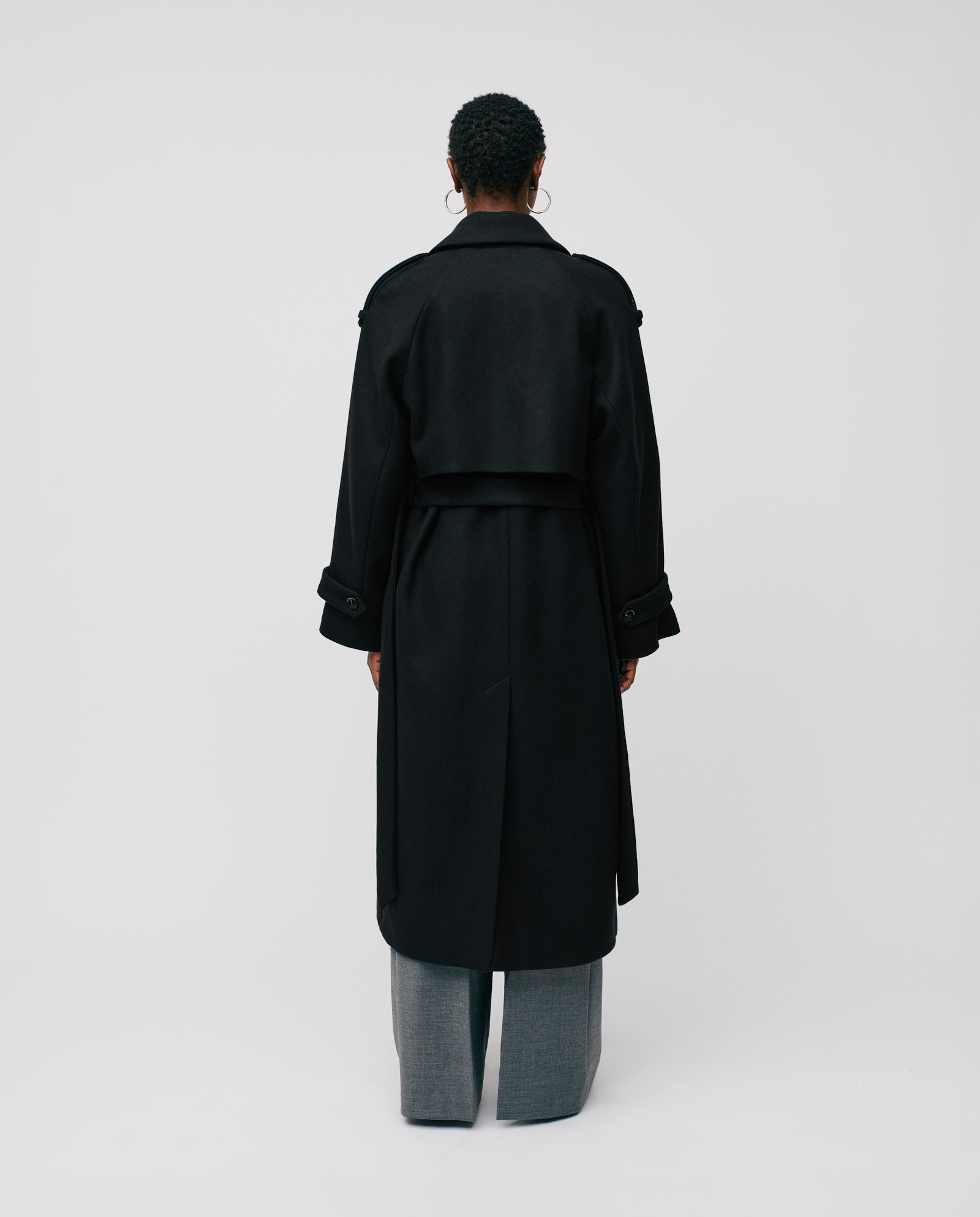 A person wearing the IVY OAK CAROLINE ANN Coat in black RWS-certified wool and gray pants, shown from the back against a plain white background.