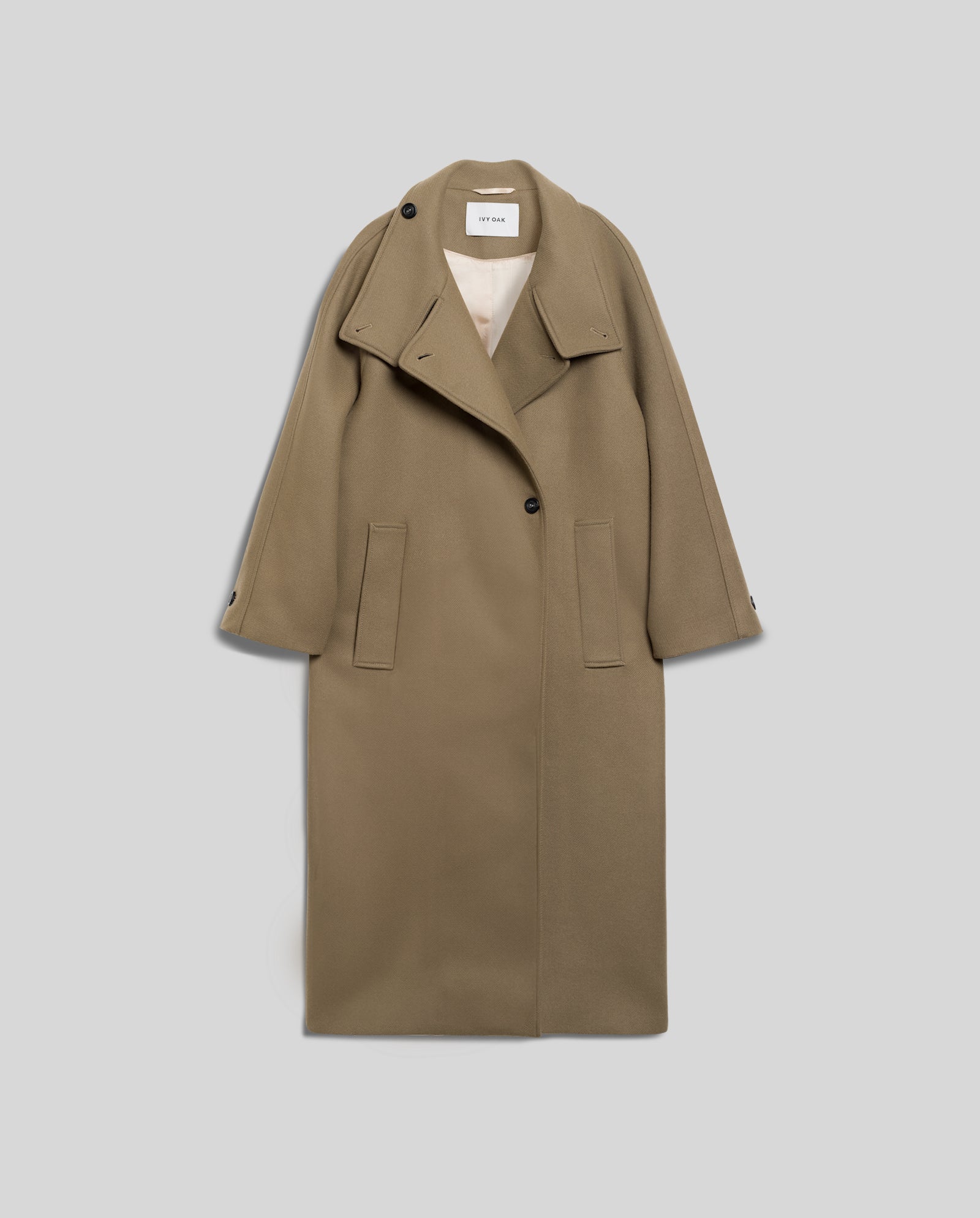 The CLEO Coat by IVY OAK is an oversized caban coat in khaki wool, designed with wide lapels, raglan sleeves, two front pockets, and a single black button.