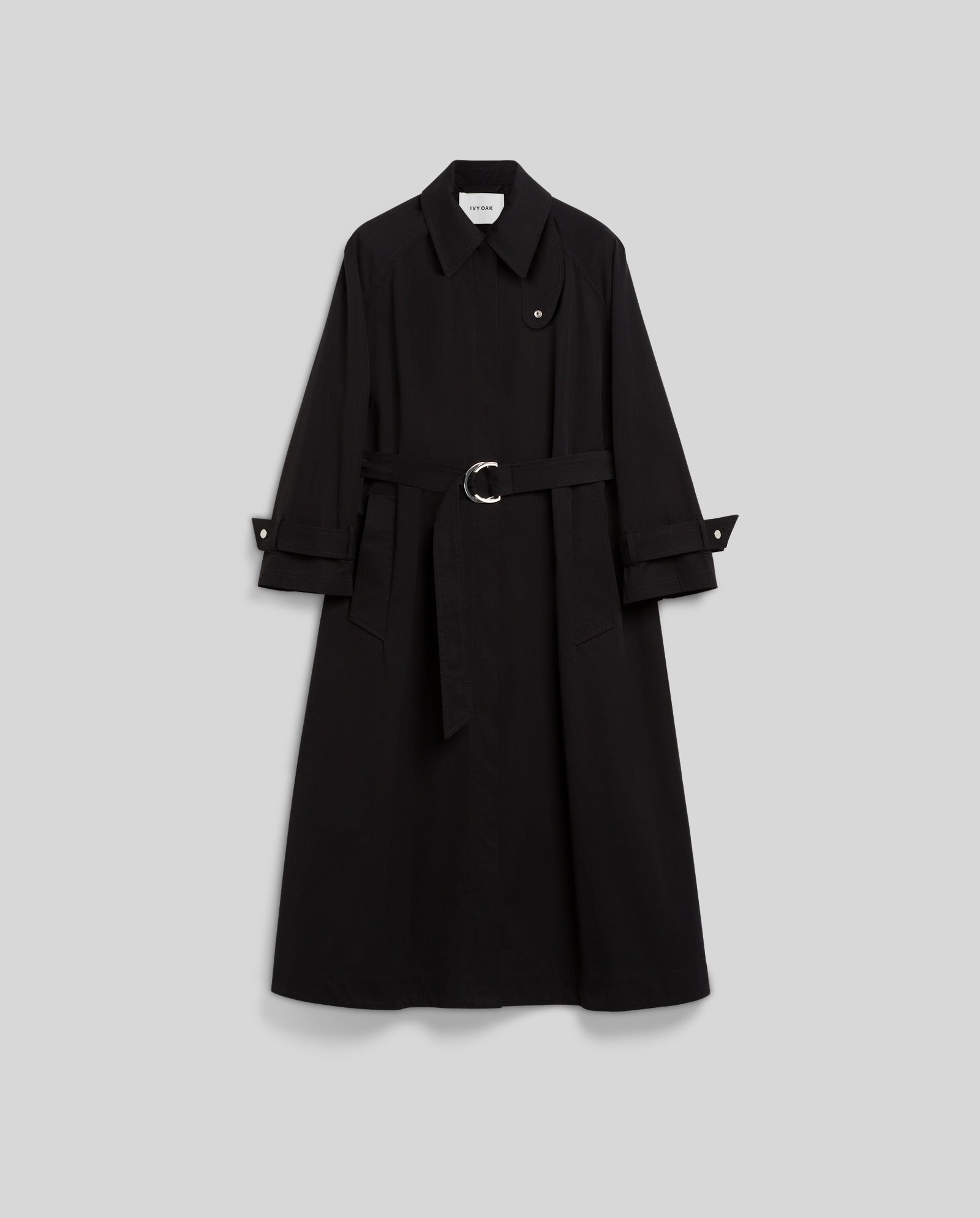 The CLEMENTINE Coat by IVY OAK is a long black A-line trench with a belted waist, wide sleeves, and a pointed collar, shown against a plain background.