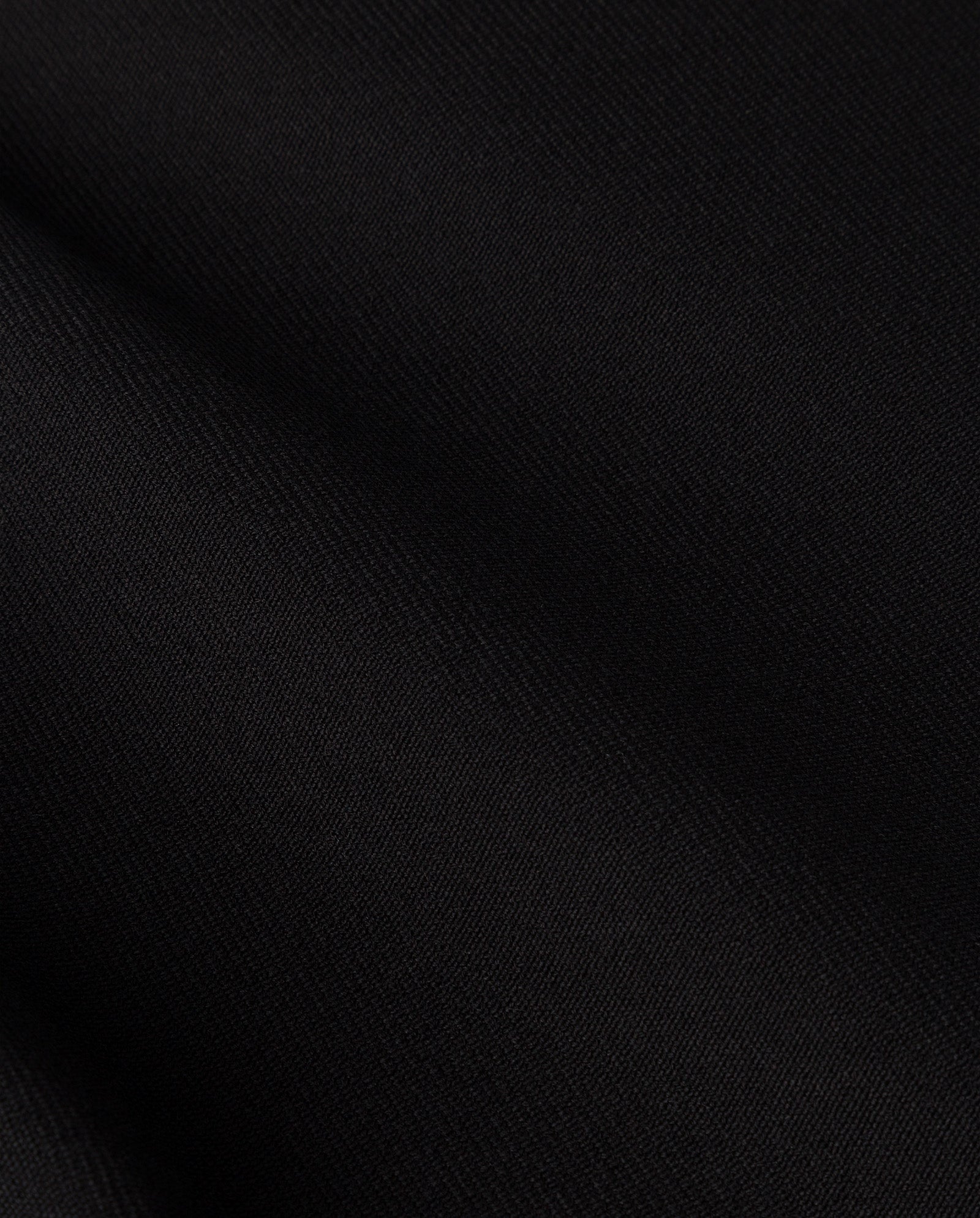 Close-up of the smooth, black fabric of the IVY OAK CORI Coat, featuring soft folds and a subtle diagonal weave pattern that evokes timeless elegance.