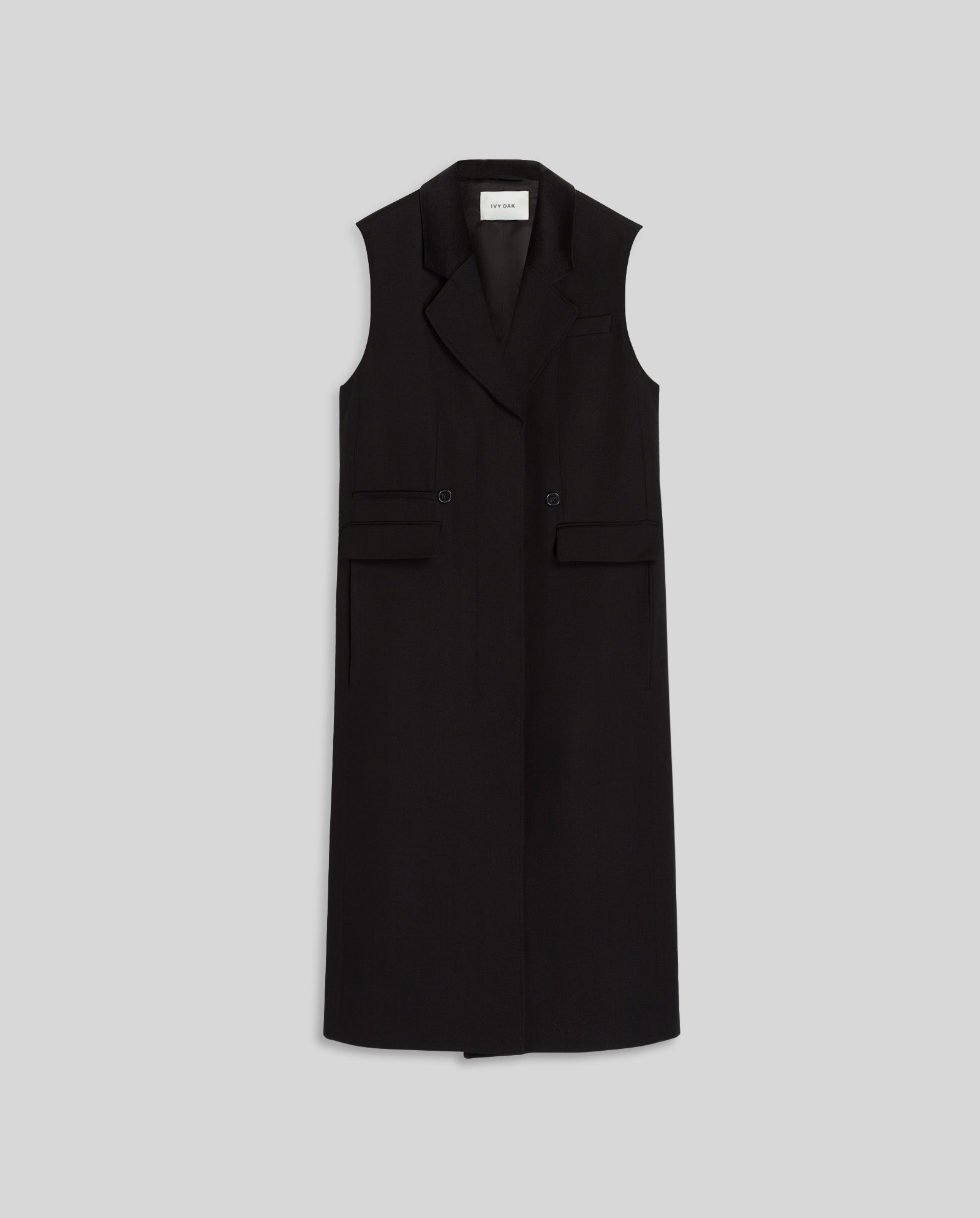 The CORI ANN Vest by IVY OAK is a sleeveless black long blazer waistcoat with lapels, pockets, and an adjustable belt, shown against a plain light gray background.