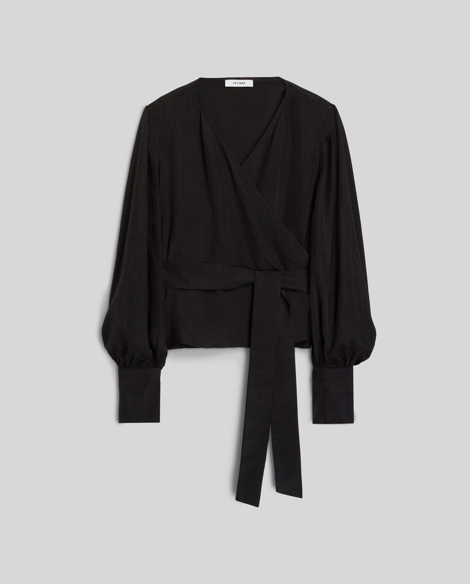 The ELOISE Top by IVY OAK is a black long-sleeve wrap blouse in airy organza, designed with a tie waist, balloon sleeves, and wide cuffs, shown on a light gray background.